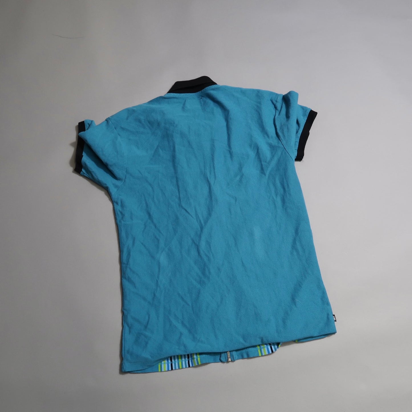 Blue polo shirt with black collar displayed on a gray background.