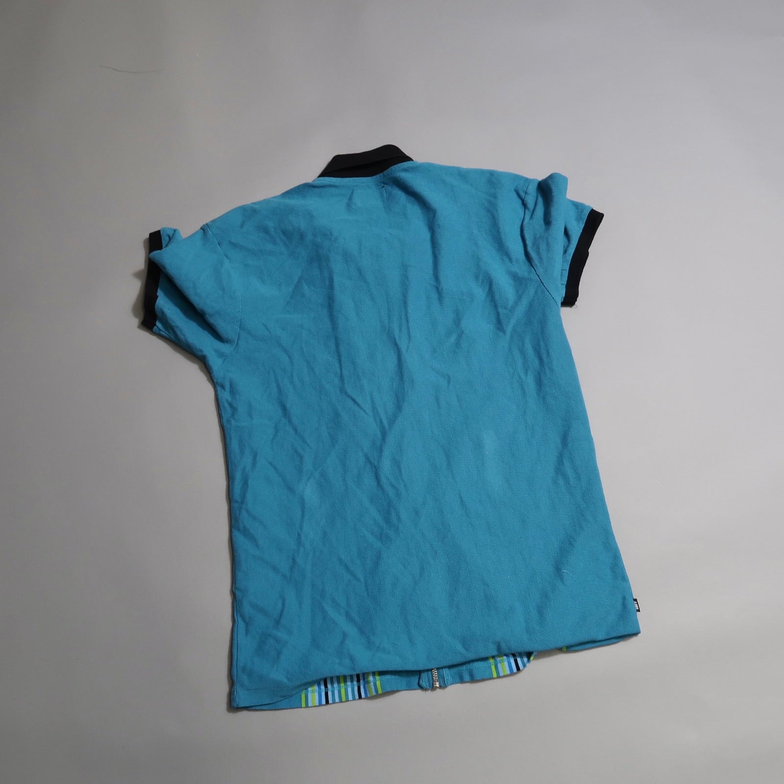 Blue polo shirt with black collar displayed on a gray background.