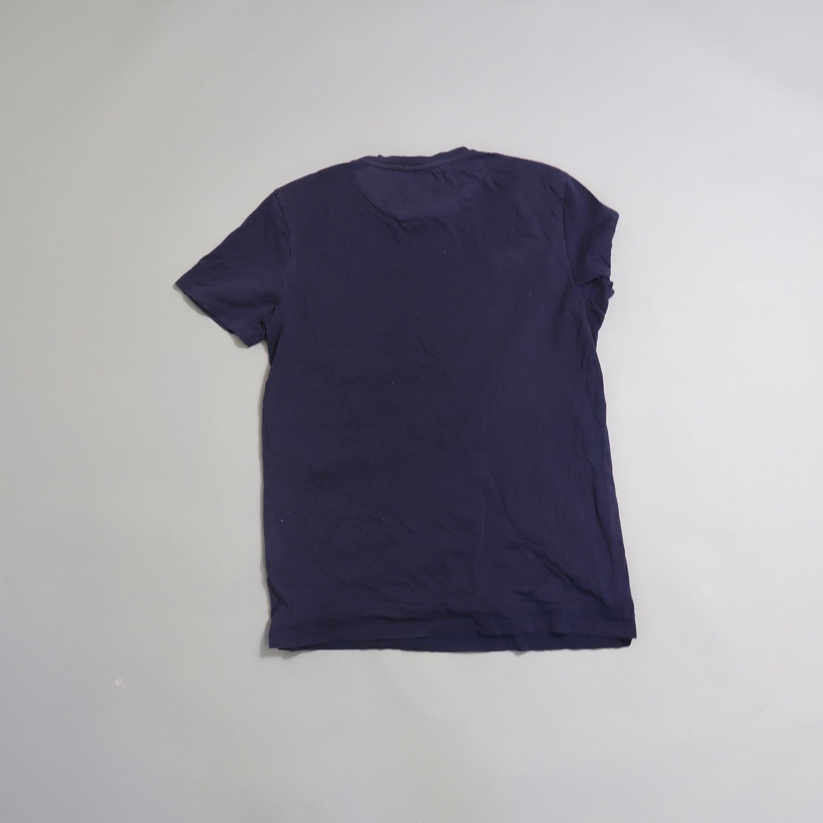 Back view of a plain navy blue T-shirt on a gray background.