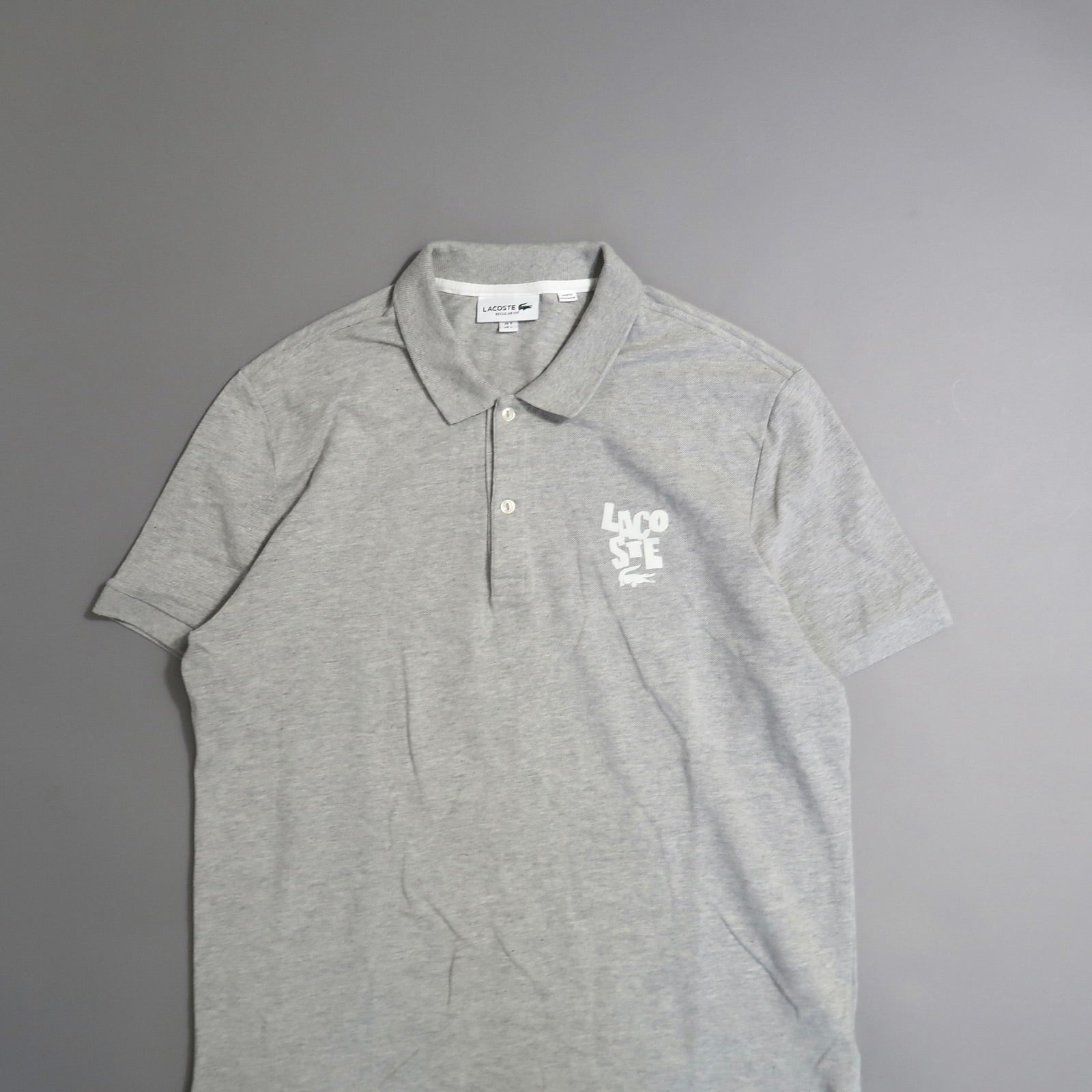 Gray Lacoste polo shirt with white logo on the chest.