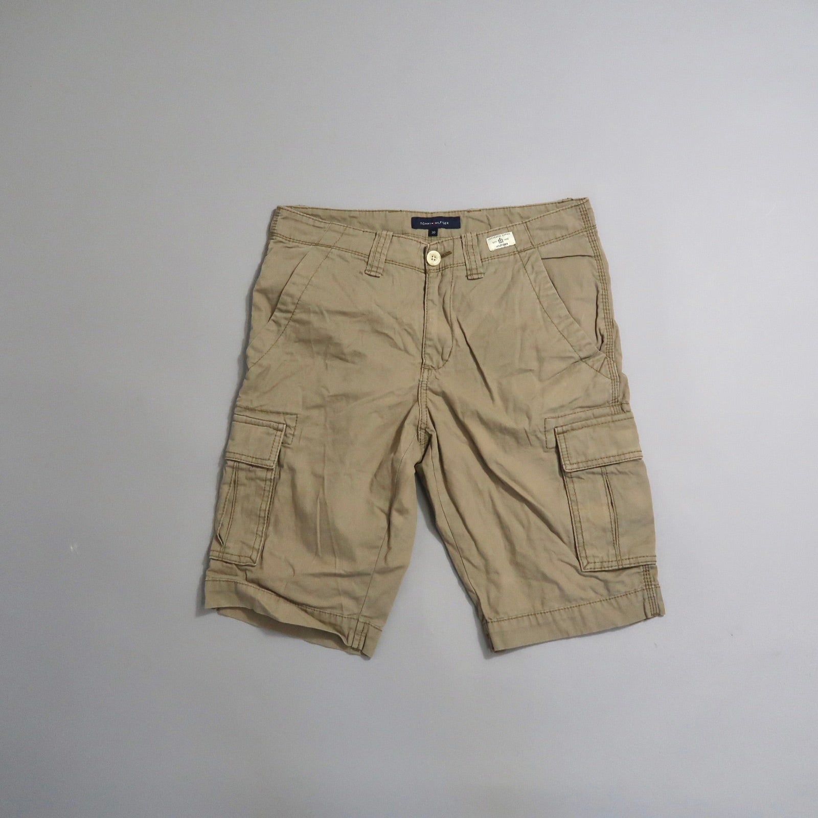 Khaki cargo shorts with multiple pockets on a light gray background.