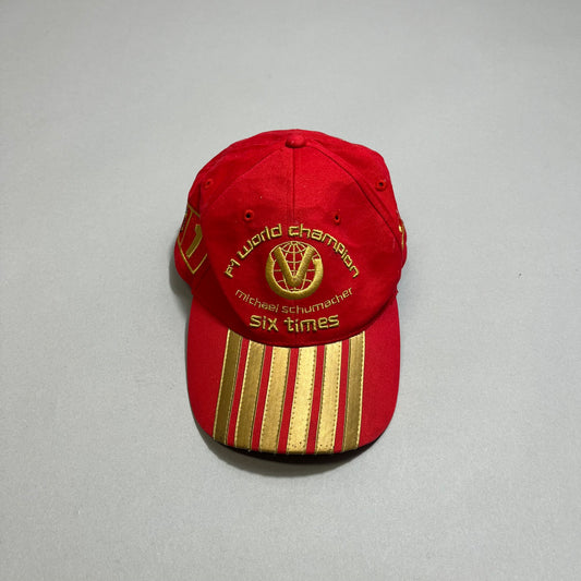 Red cap with nullF1 World Championnull and gold stripes design.