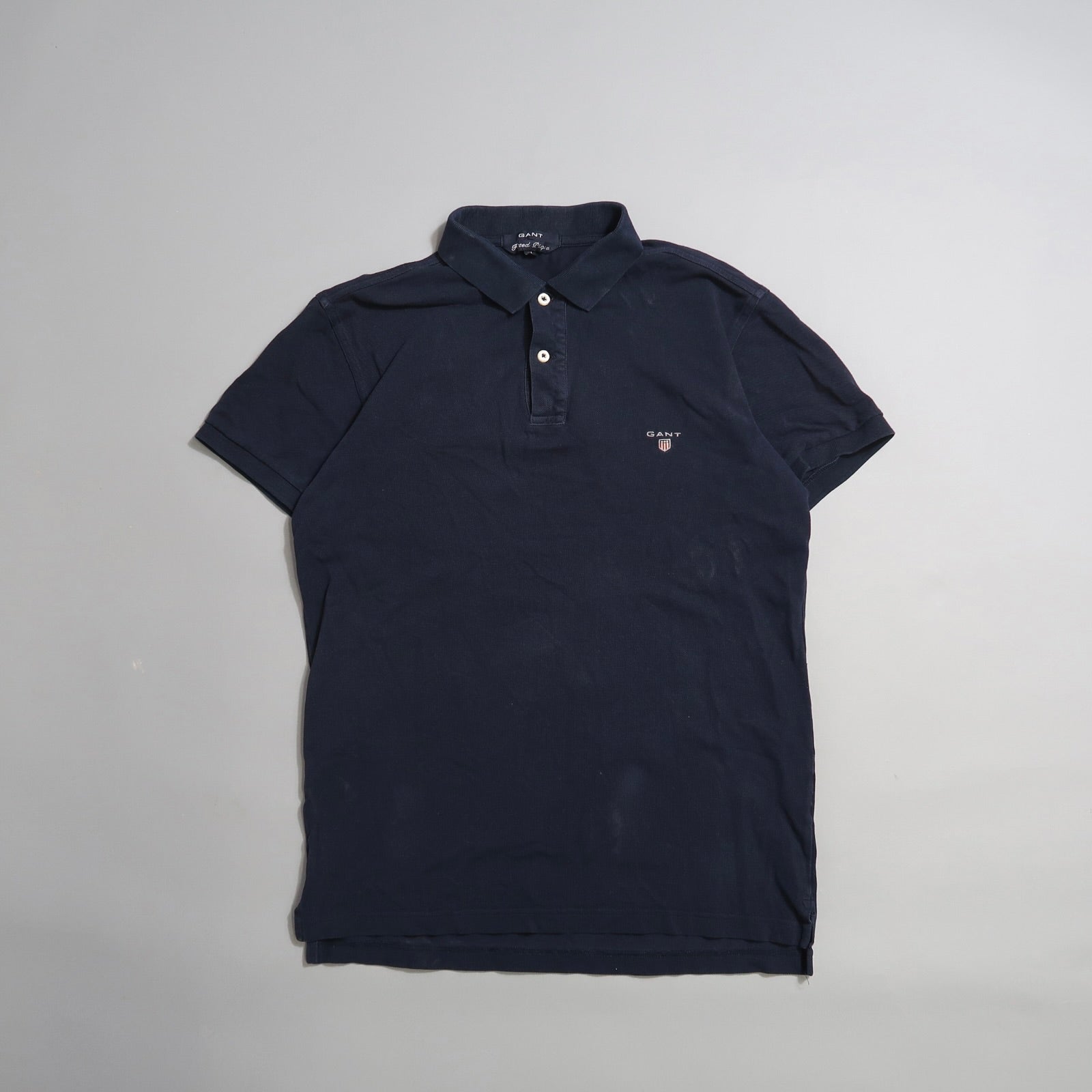 Dark blue polo shirt with a small logo on the chest, laid flat.