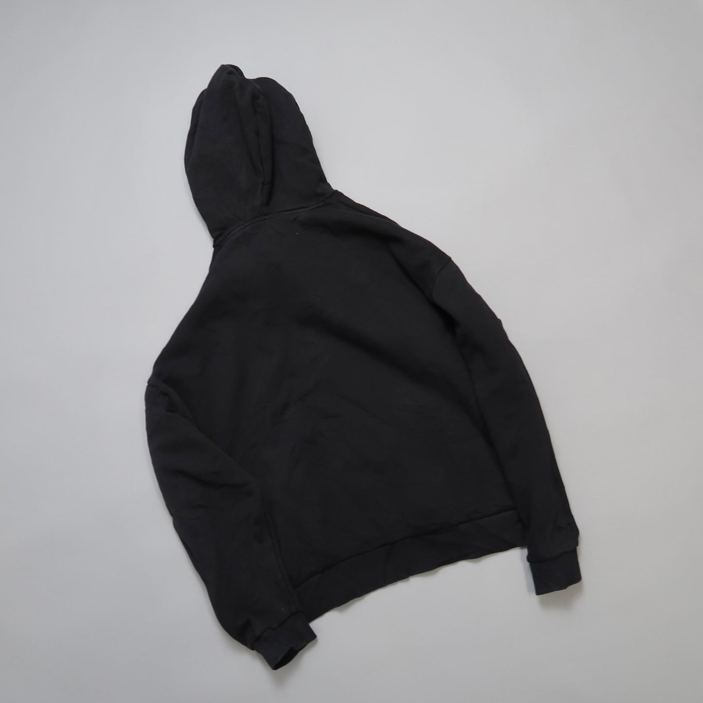 Black hoodie laid flat on a neutral background.