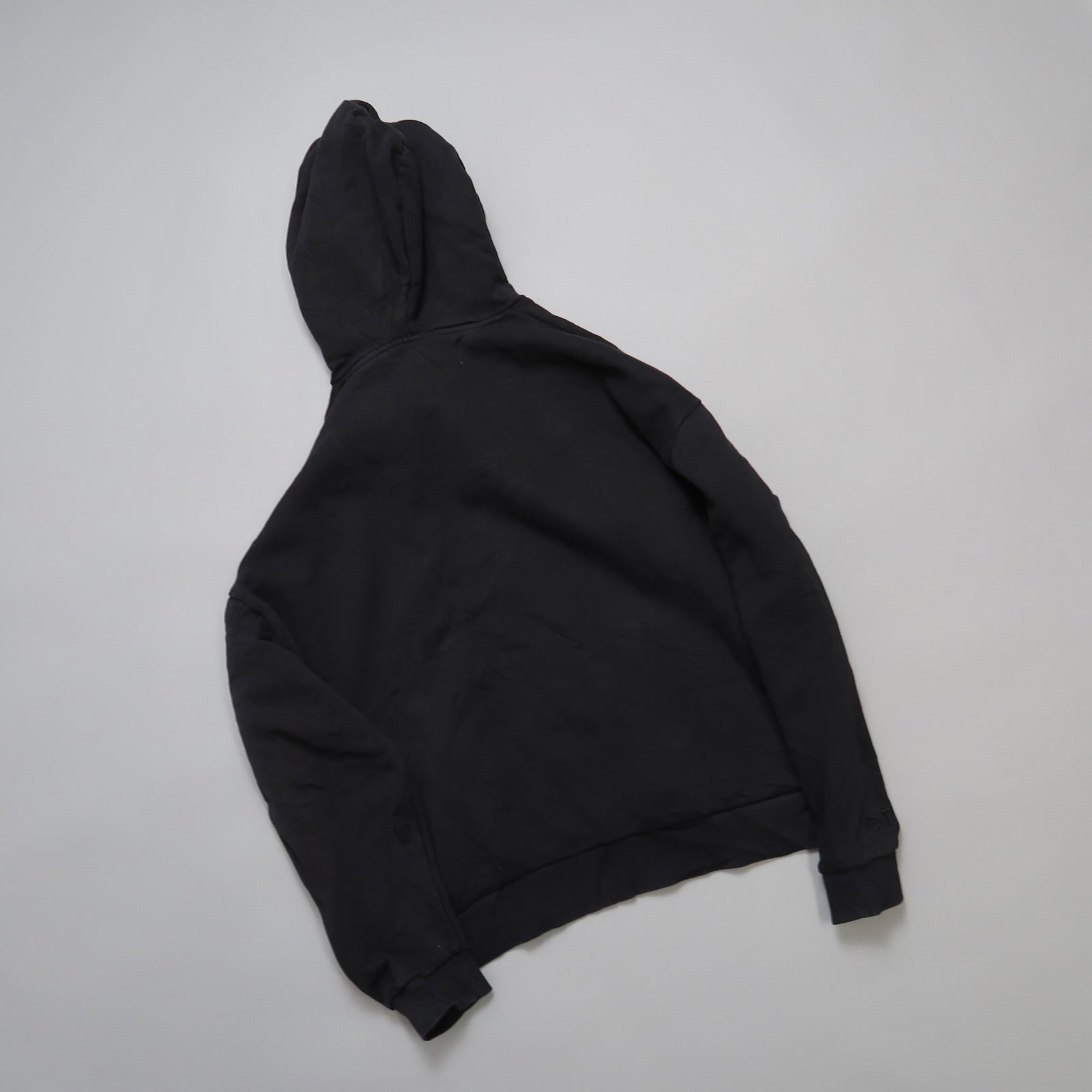 Black hoodie laid flat on a neutral background.