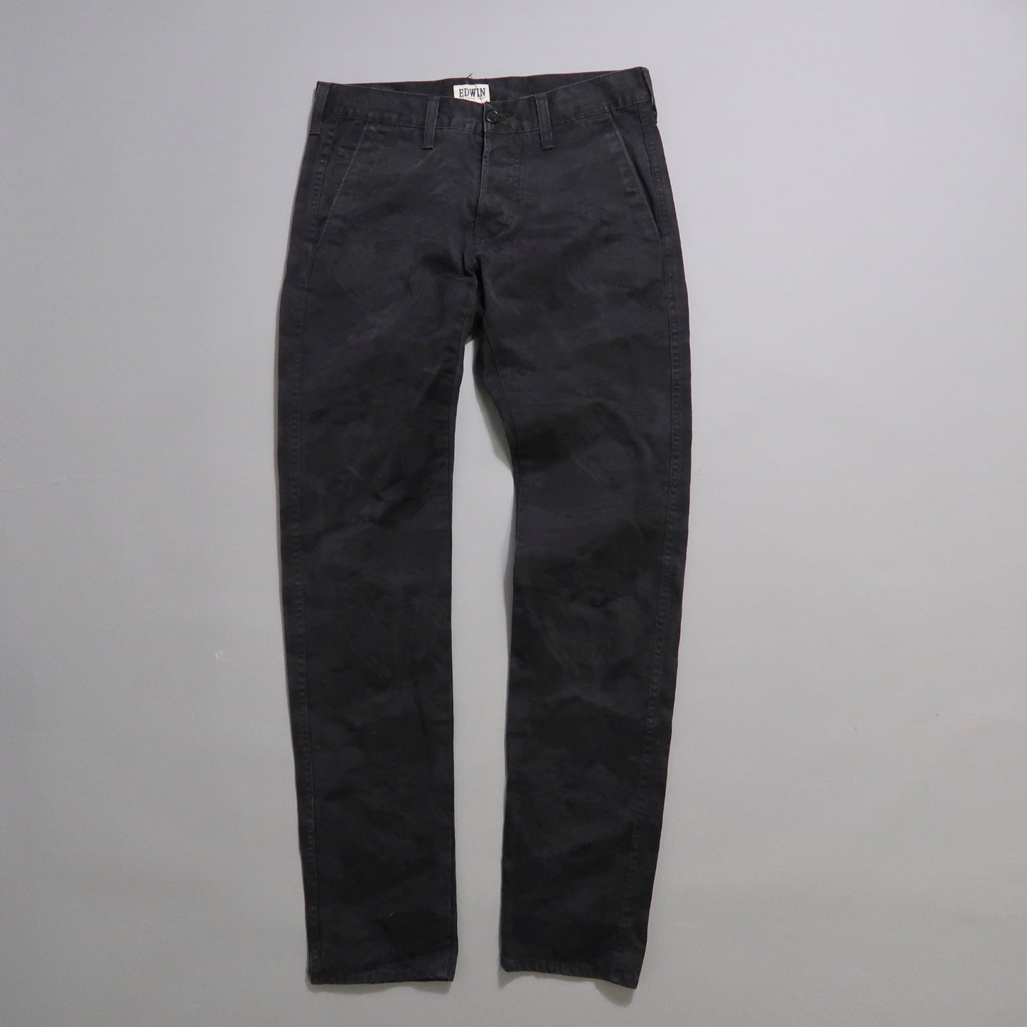 Black trousers laid flat on a light gray background.
