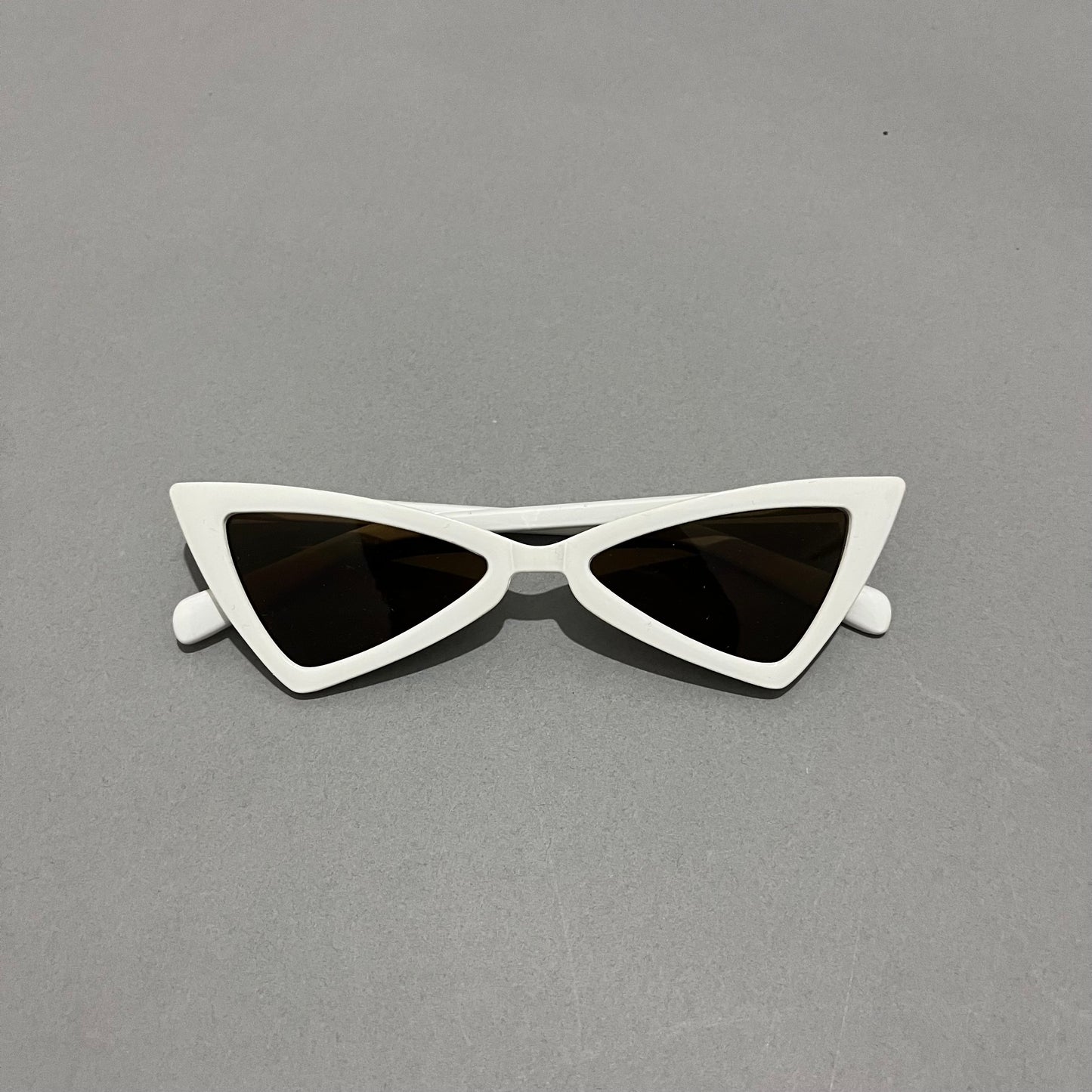 White, cat-eye sunglasses with dark lenses on a gray background.