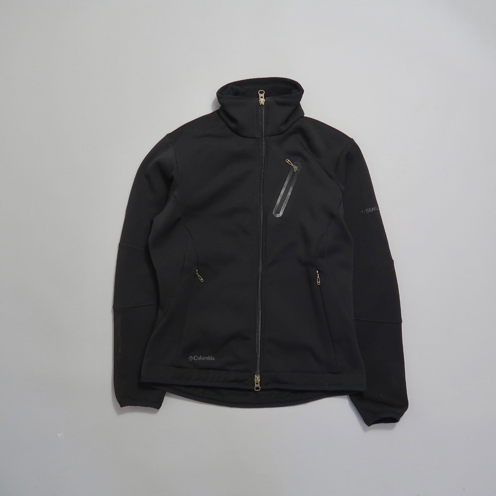 Black Columbia jacket with zipper pockets on a light background.