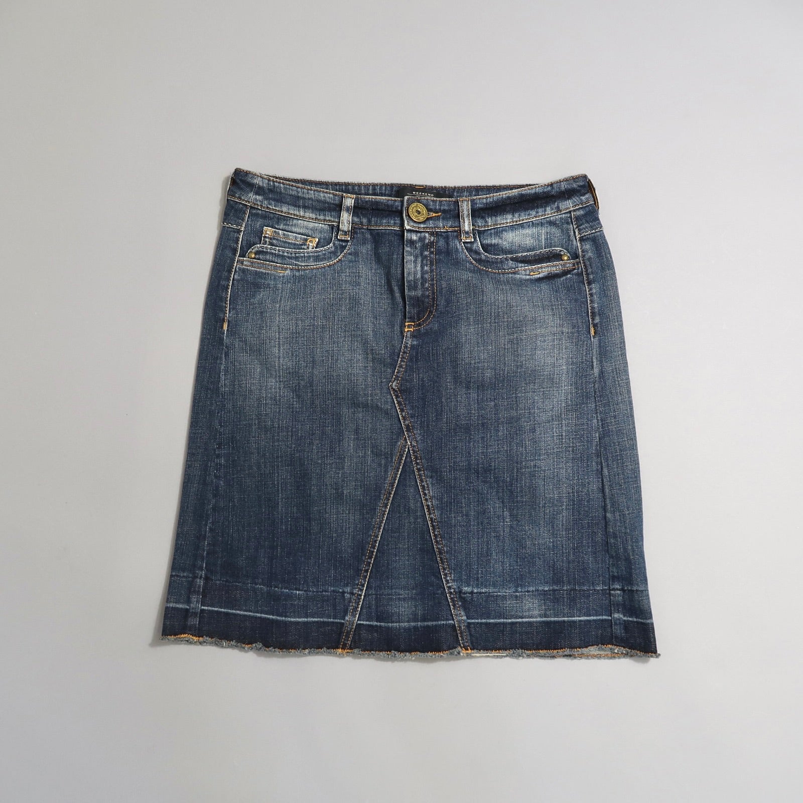 Denim skirt with pockets and button, laid flat on a white surface.