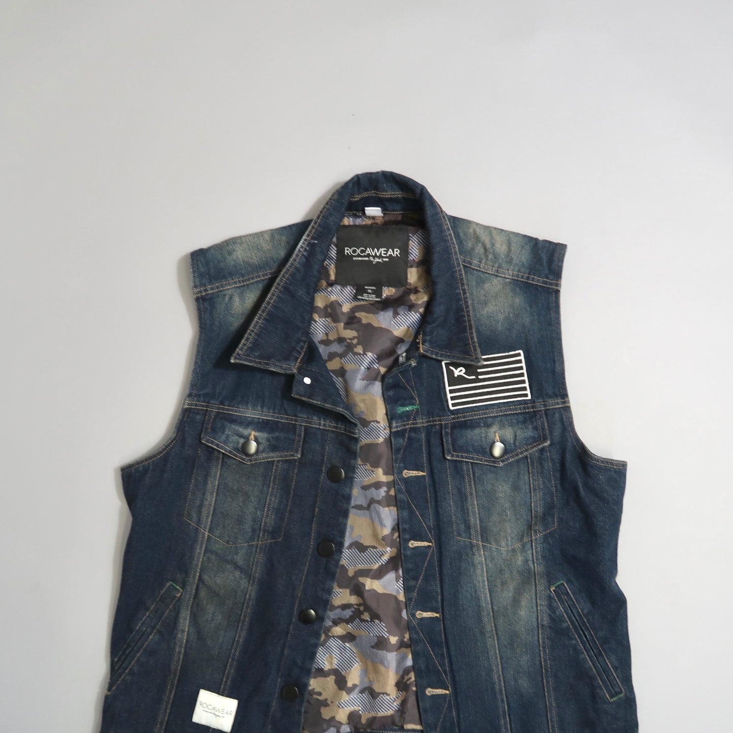 Denim vest with camo lining and patch detail on the front.