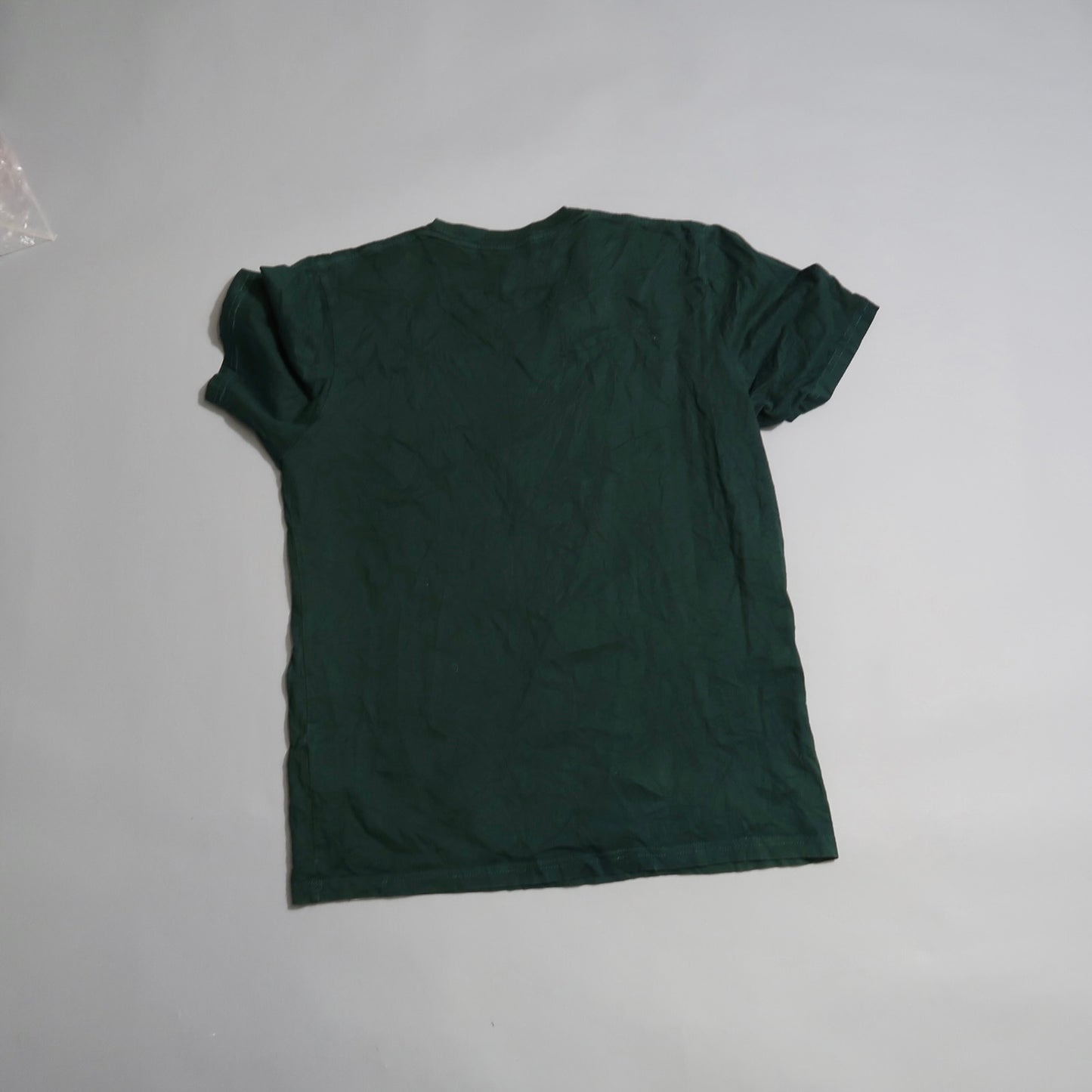 Dark green t-shirt laid flat on a gray background.