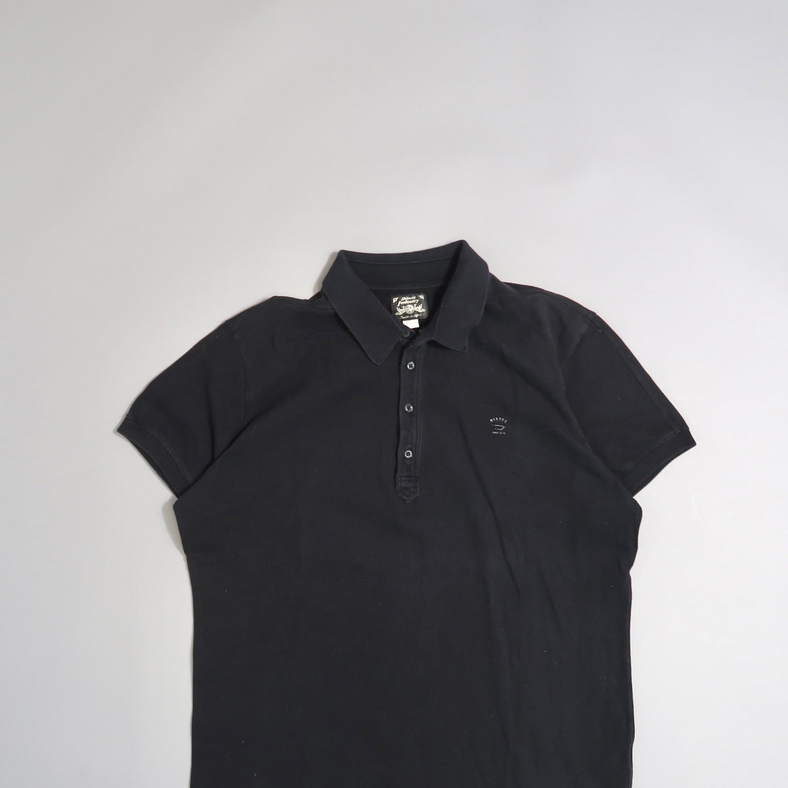 Black polo shirt on a neutral background.