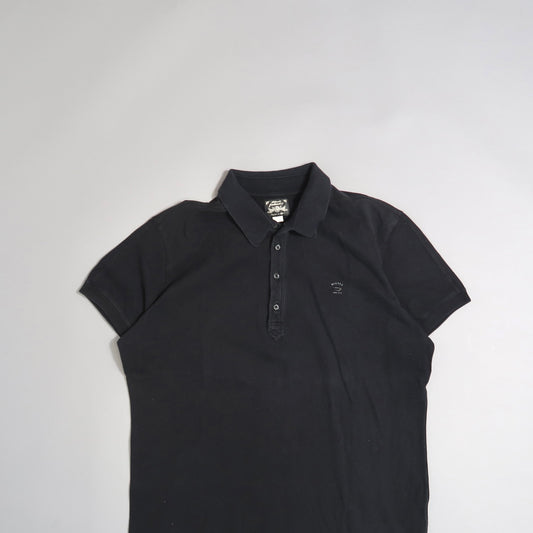 Black polo shirt on a neutral background.