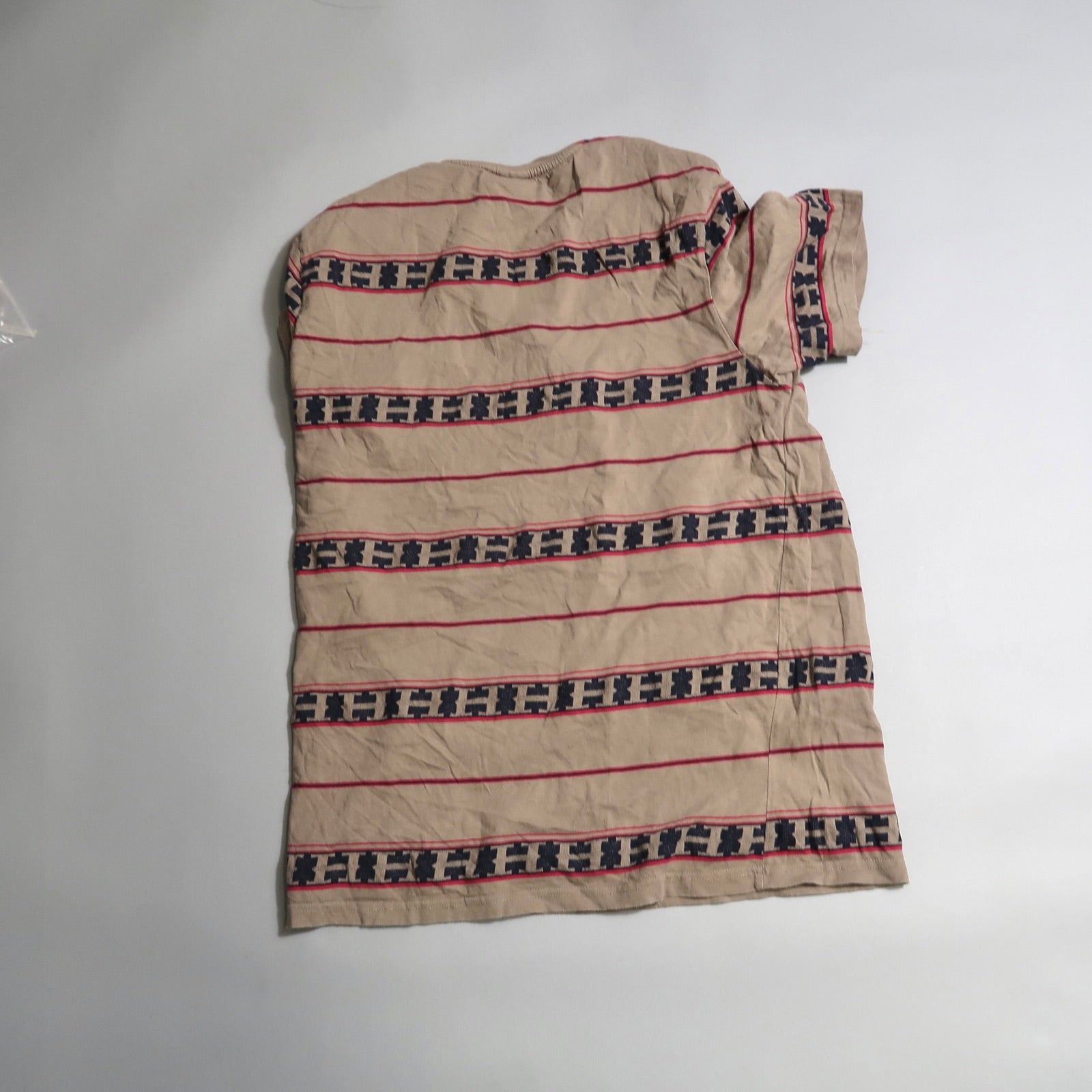 Beige striped shirt with geometric patterns on white background.