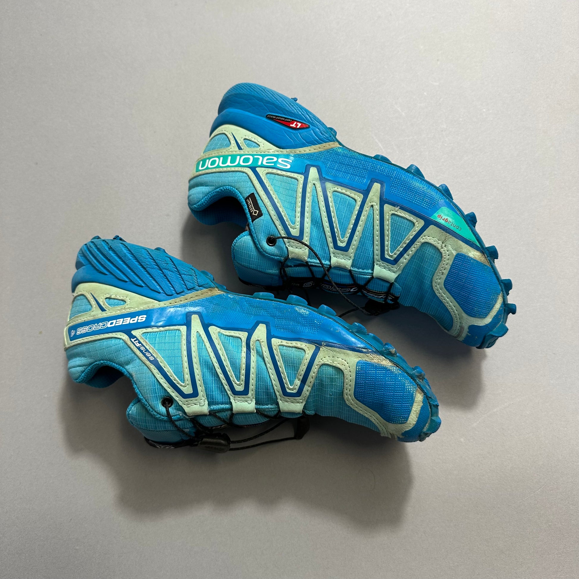 Blue and teal trail running shoes with prominent tread pattern.