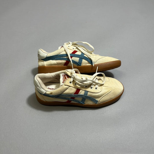 Beige sneakers with red and blue stripes on a gray background.