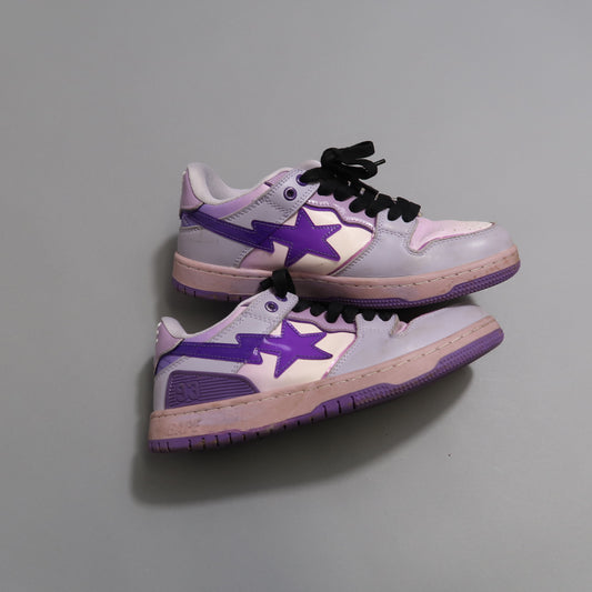 Purple and pink sneakers with black laces on a gray surface.