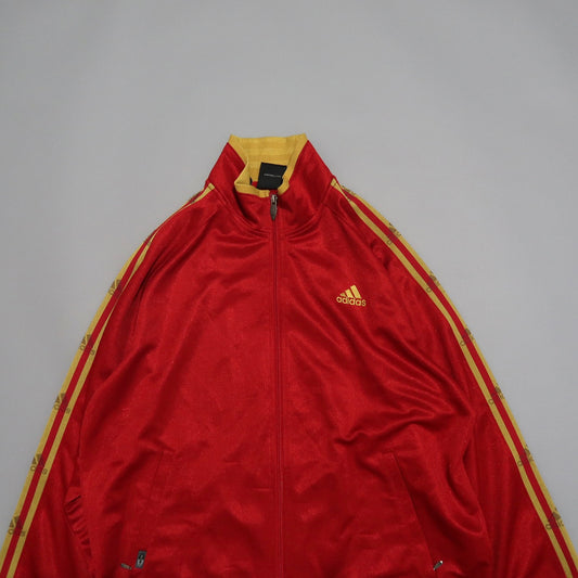 Red and yellow Adidas jacket with zip and logo on the front.