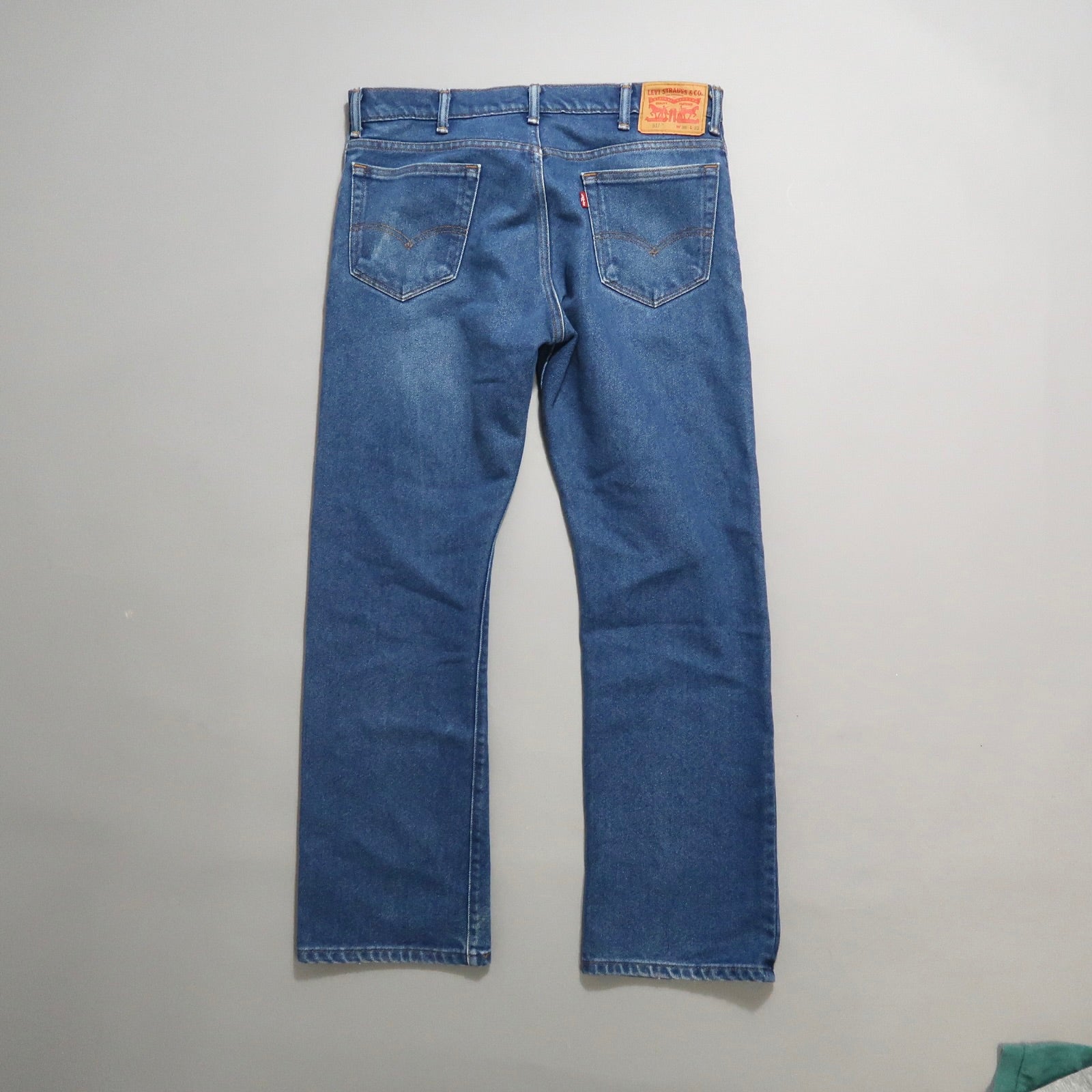 Back view of blue jeans against a gray background.