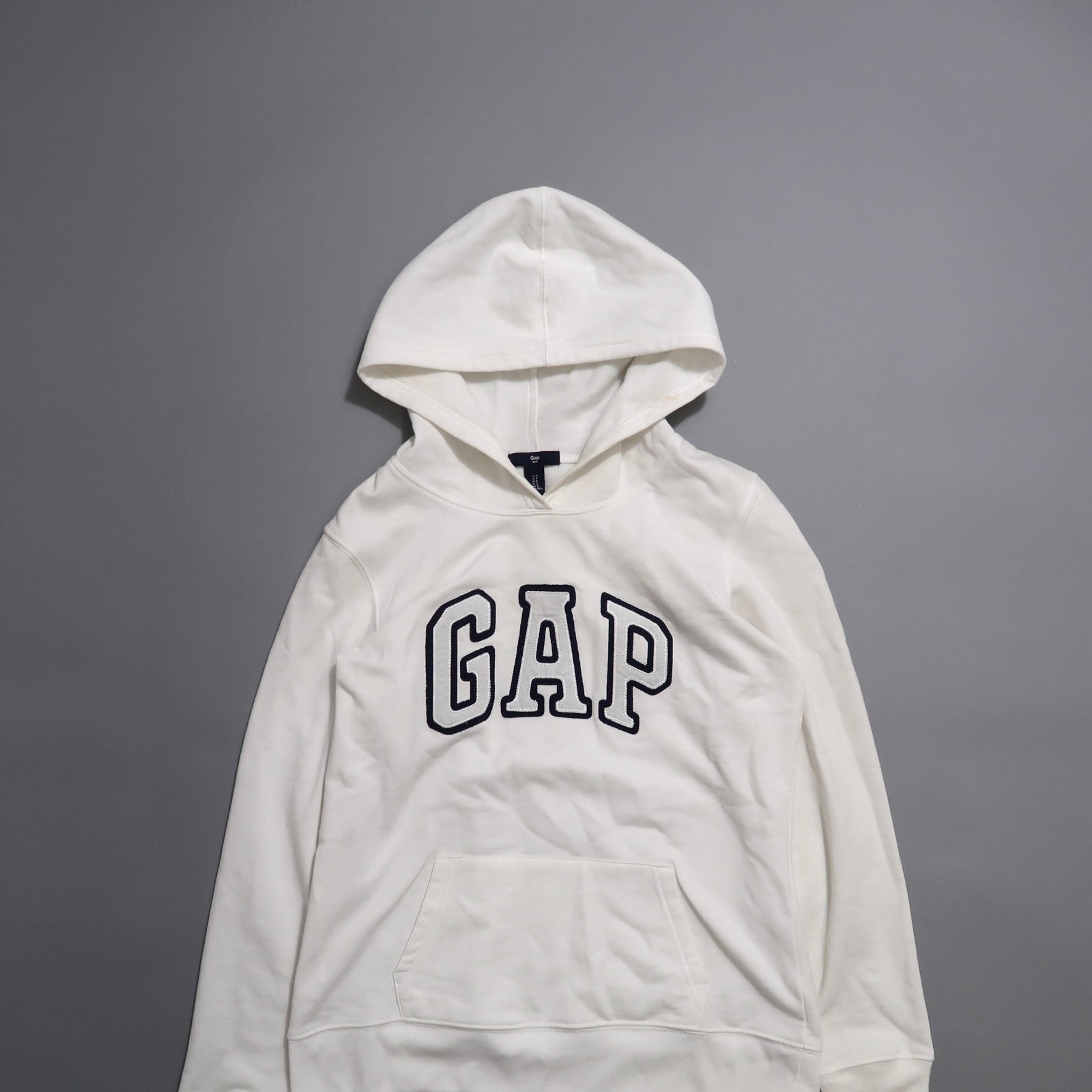 White GAP hoodie on a gray background.
