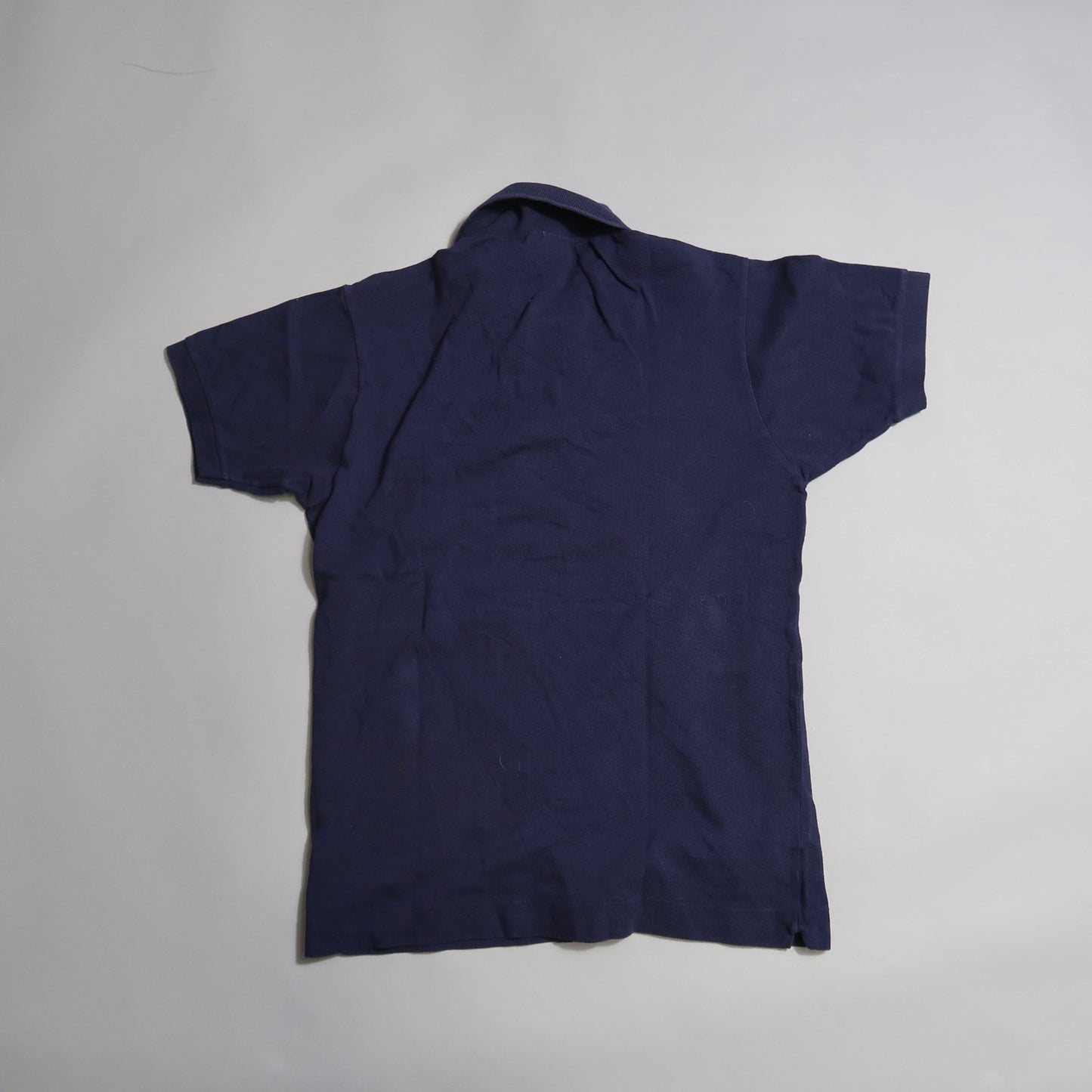 Navy blue short-sleeve shirt lying flat on a light surface.