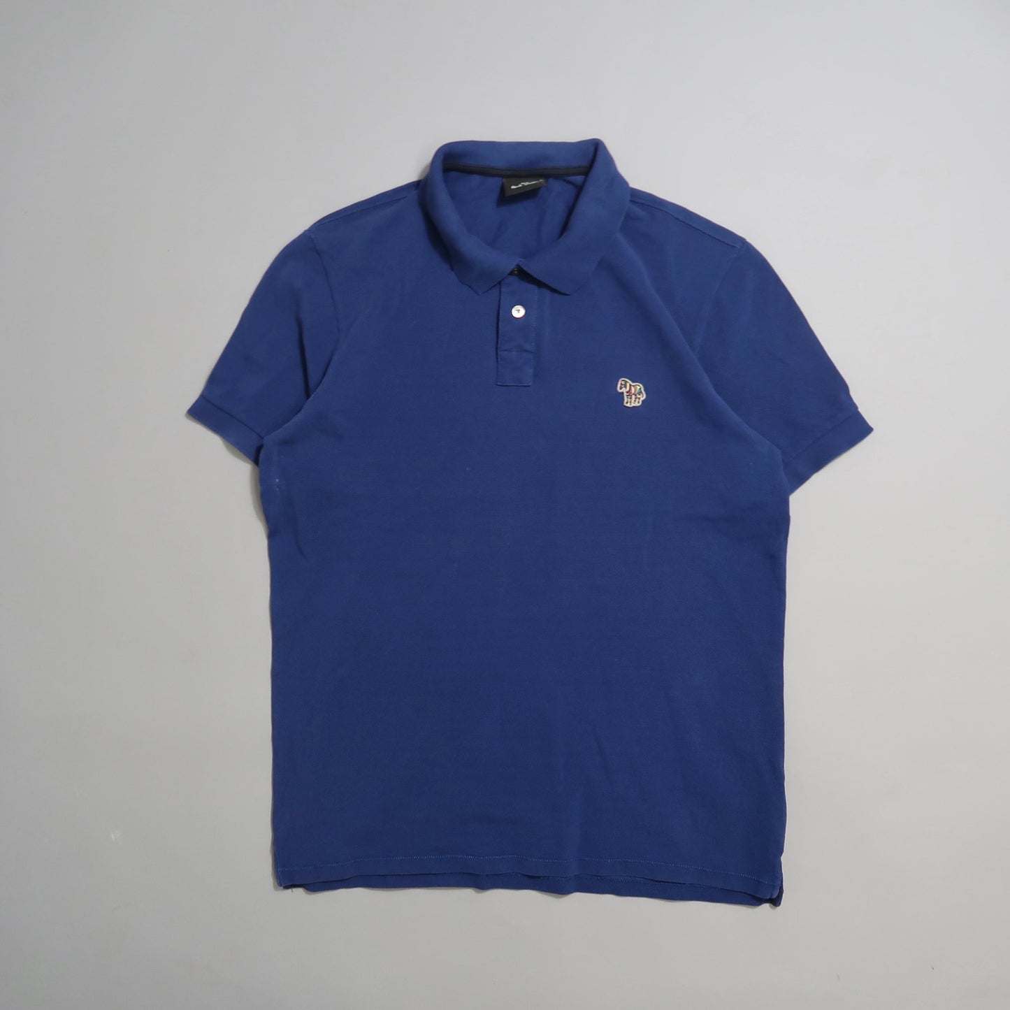 Blue polo shirt with a small embroidered logo on the chest.