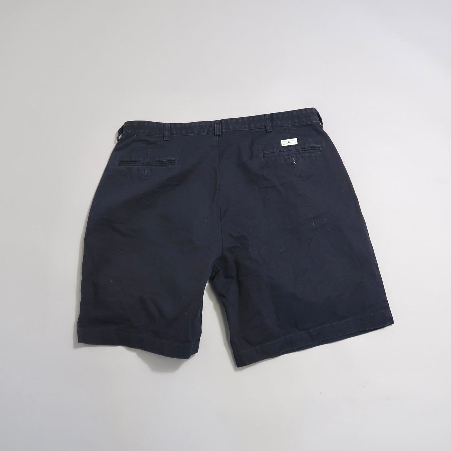 Back view of black shorts with pockets on a plain background.