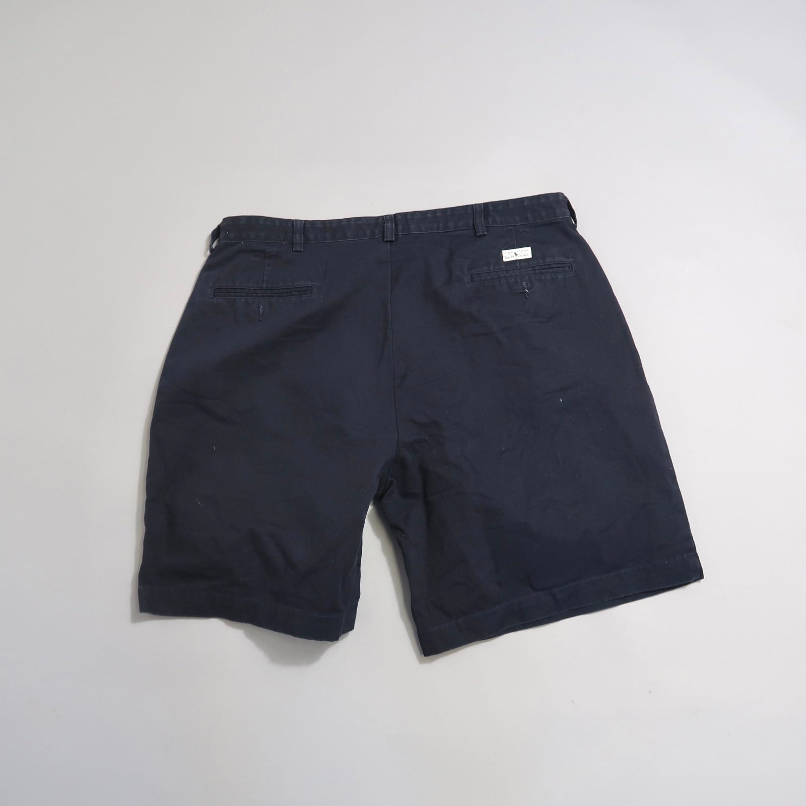 Back view of black shorts with pockets on a plain background.