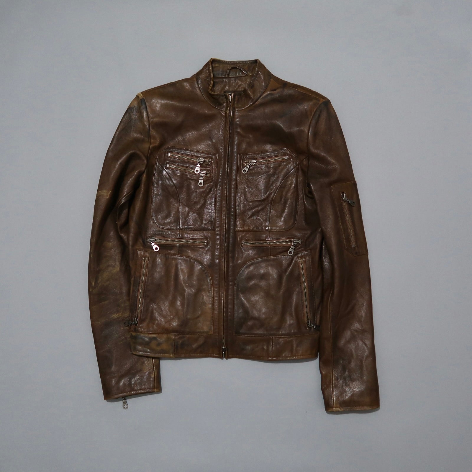 Brown leather jacket with multiple zippered pockets.