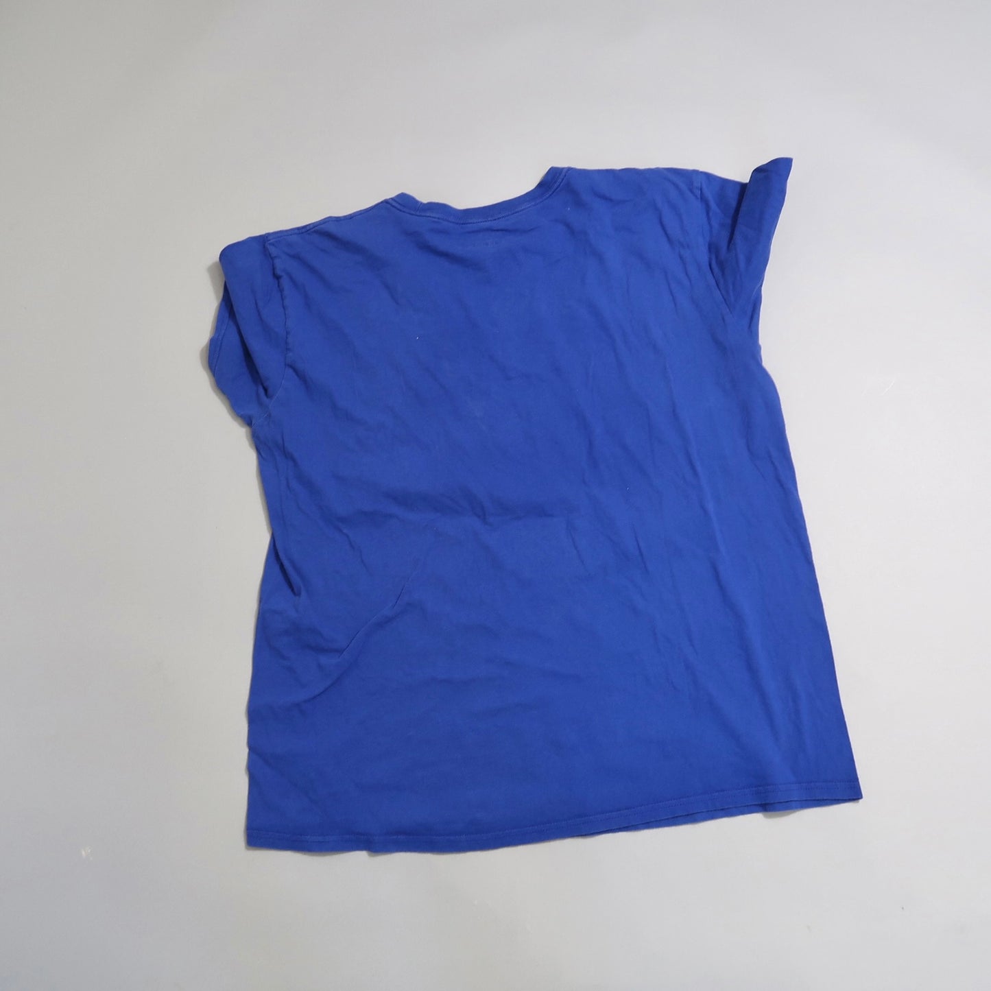 Wrinkled blue t-shirt lying flat on a light surface.