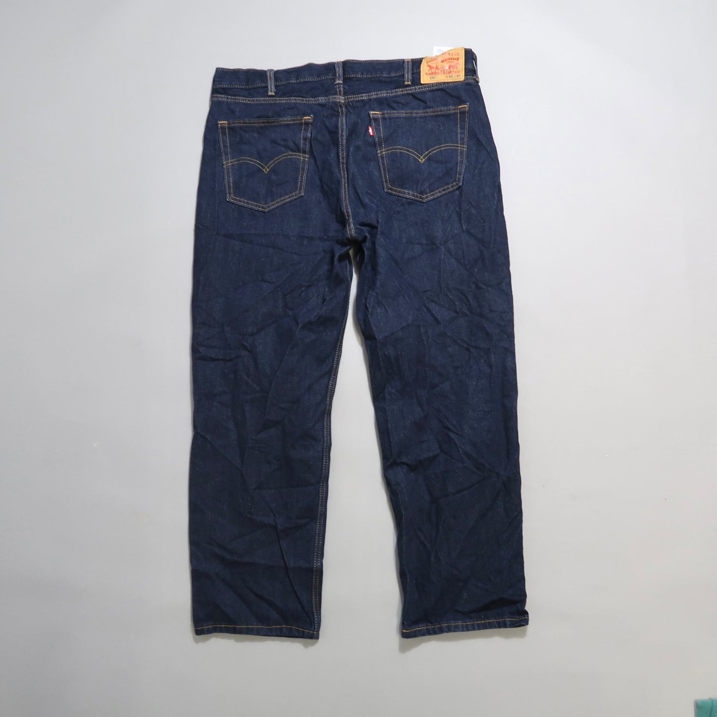 Back view of dark blue jeans with a leather patch on the waistband.