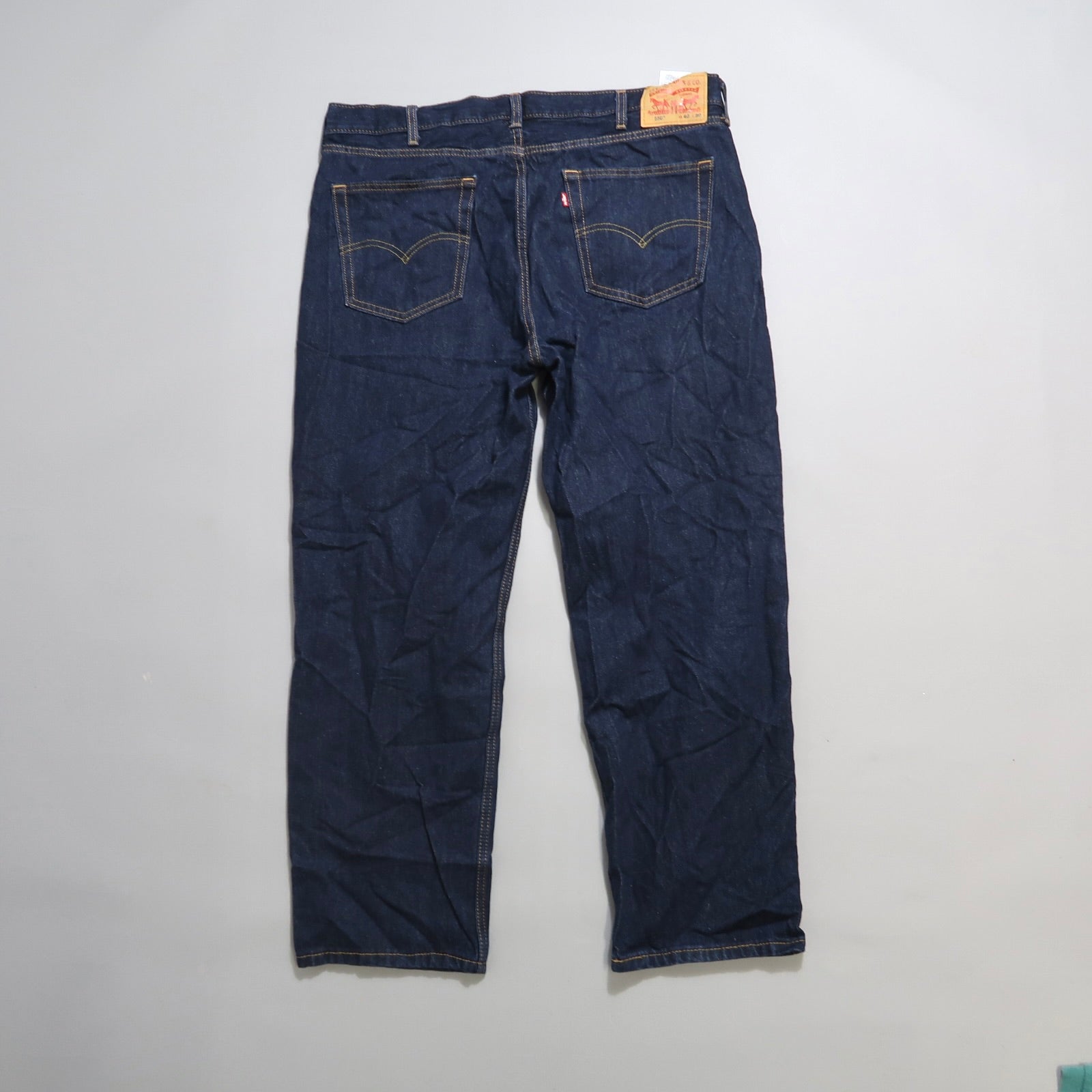 Back view of dark blue jeans with a leather patch on the waistband.