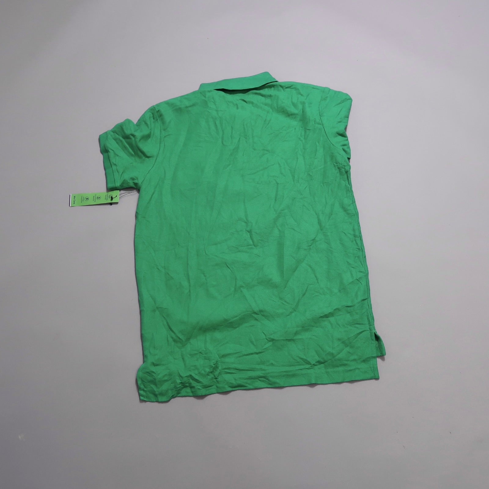 Green polo shirt laid flat with a tag attached.