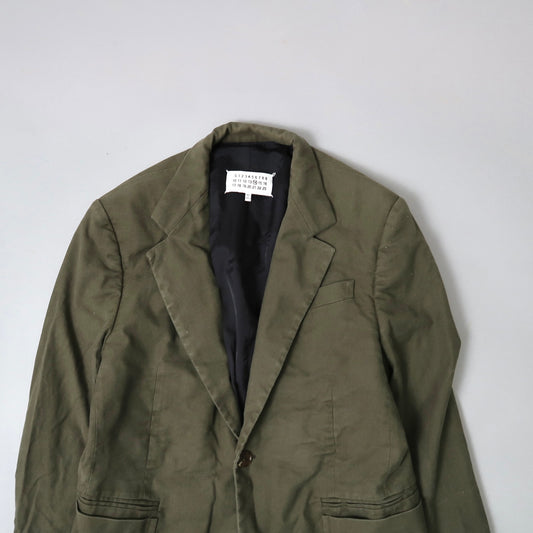 Olive green blazer on gray background with visible inner label.