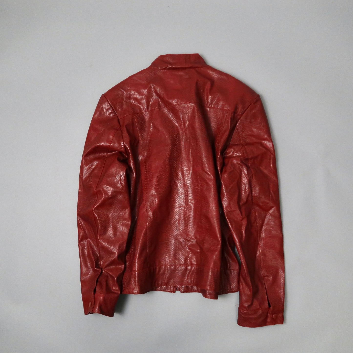 Back view of a red leather jacket on a neutral background.