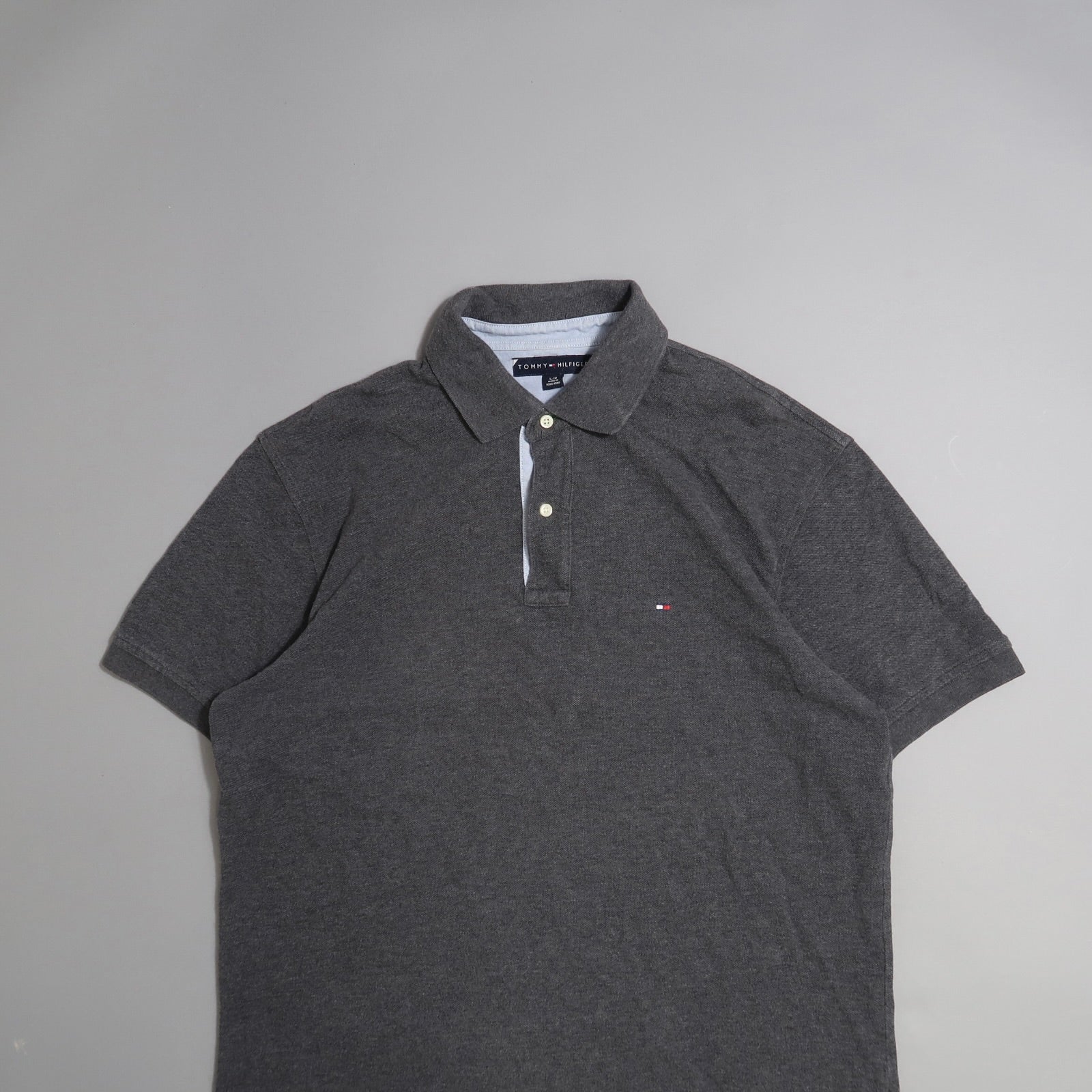 Dark gray polo shirt with collar and short sleeves on plain background.