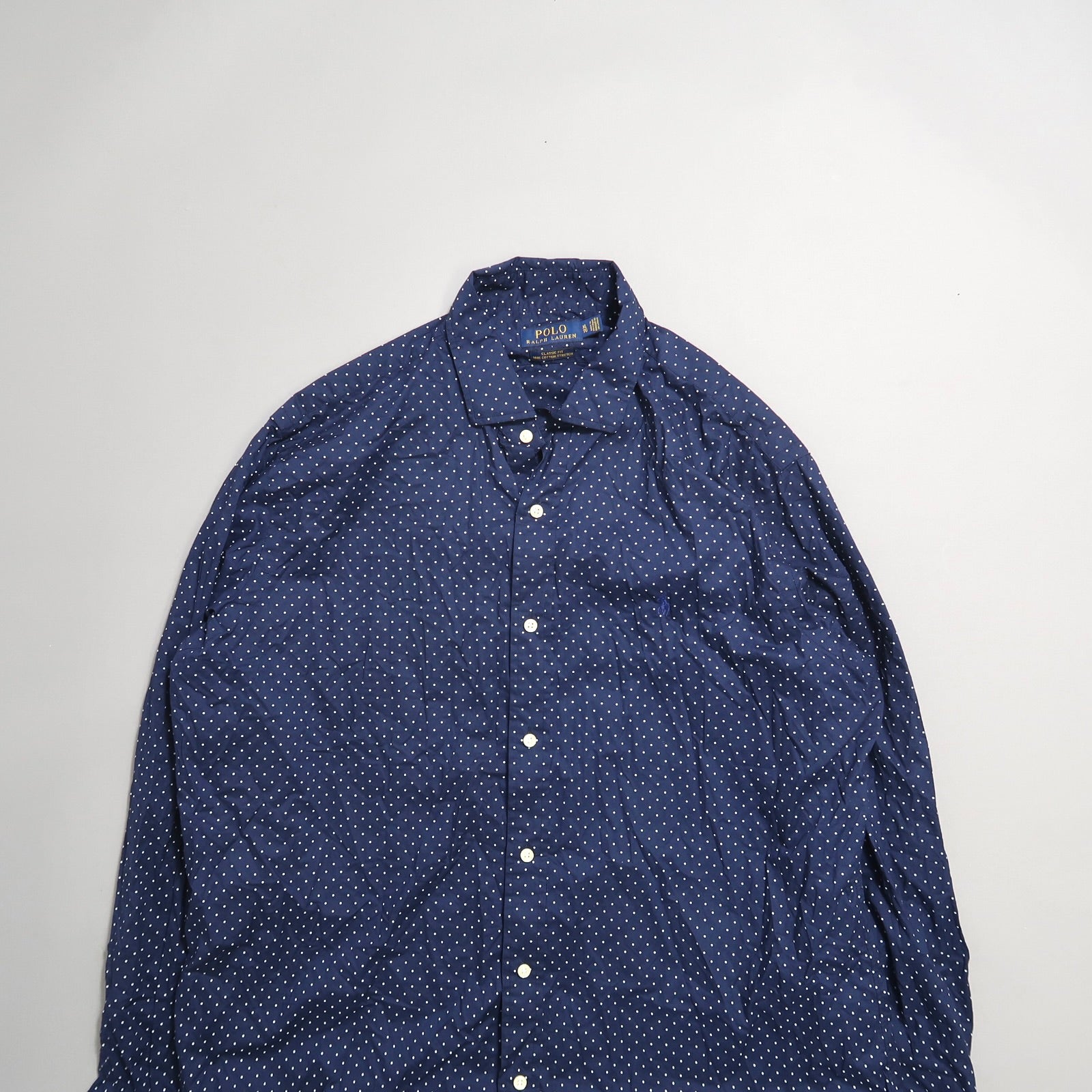 Blue and white polka dot button-up shirt on a plain background.