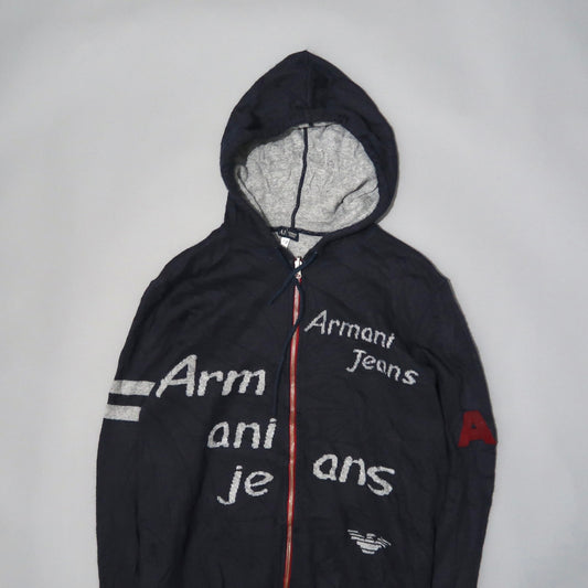 Dark hooded jacket with scattered text and red zipper.