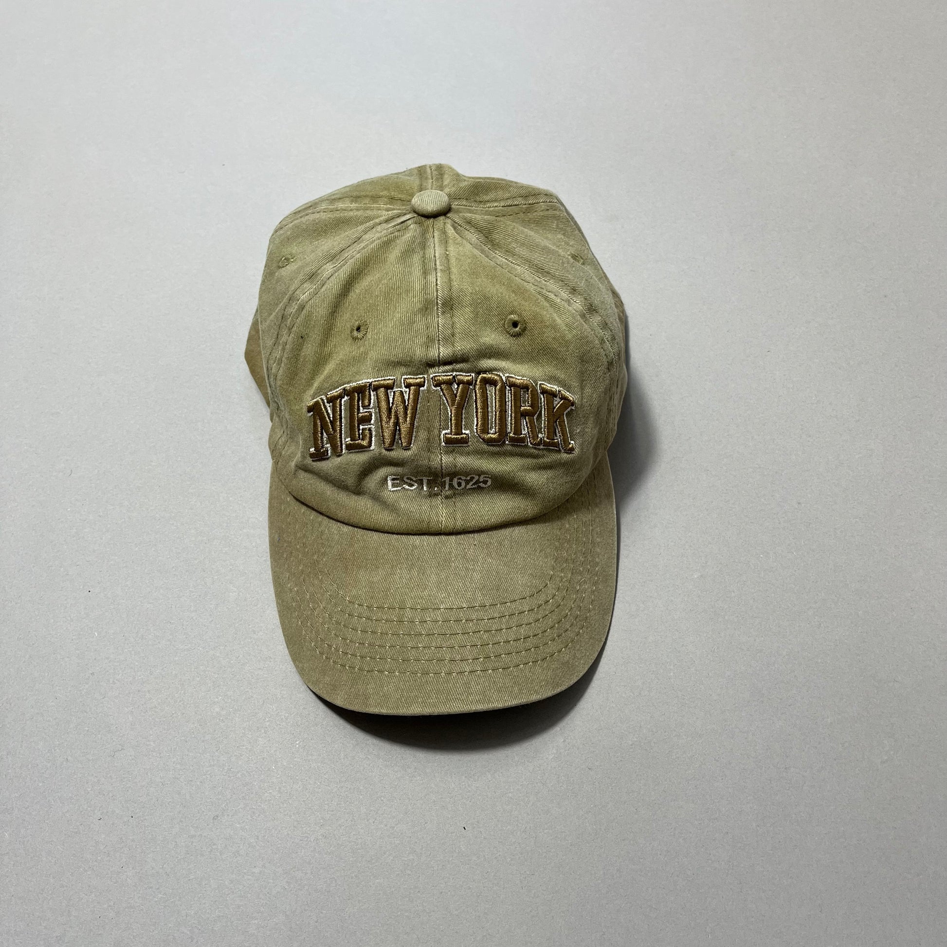 Olive green cap with nullNew Yorknull and nullEst. 1625null embroidered on it.