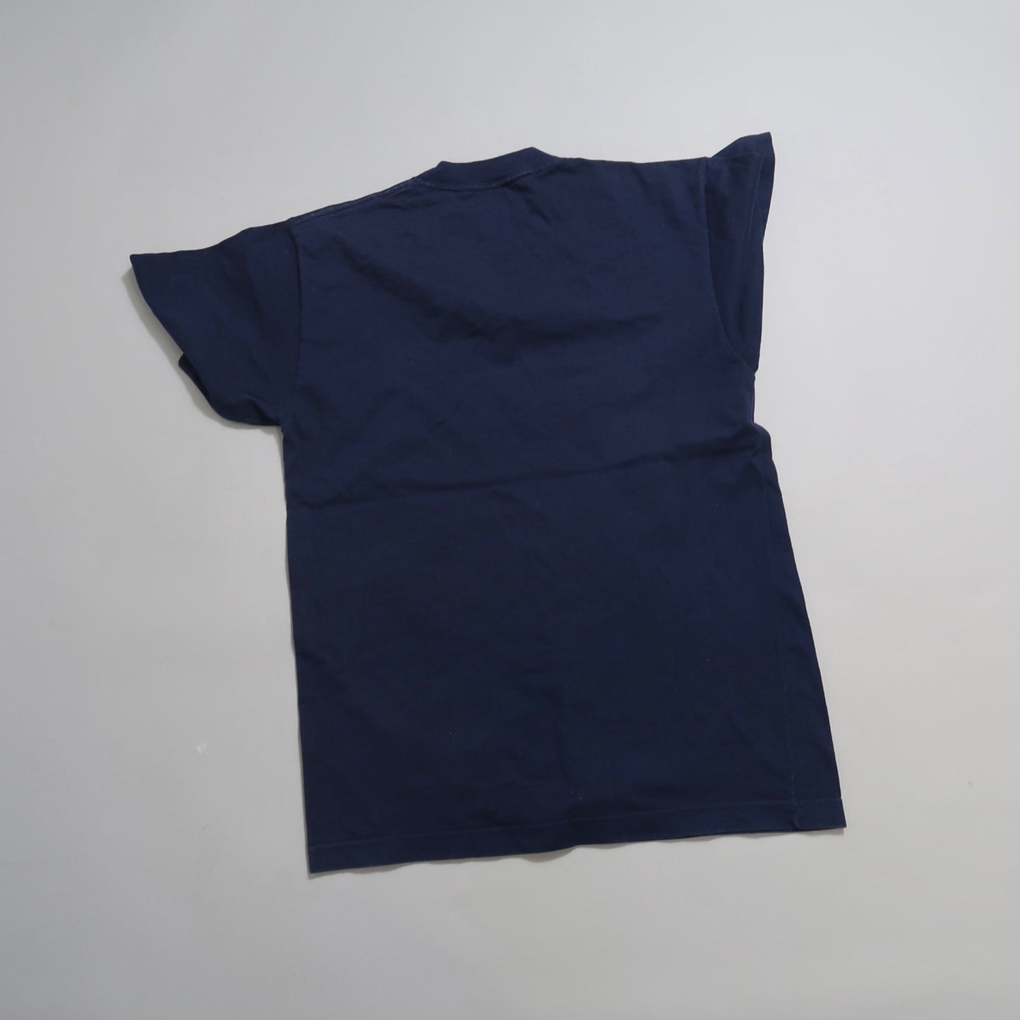 Navy blue T-shirt laid flat on a light surface.