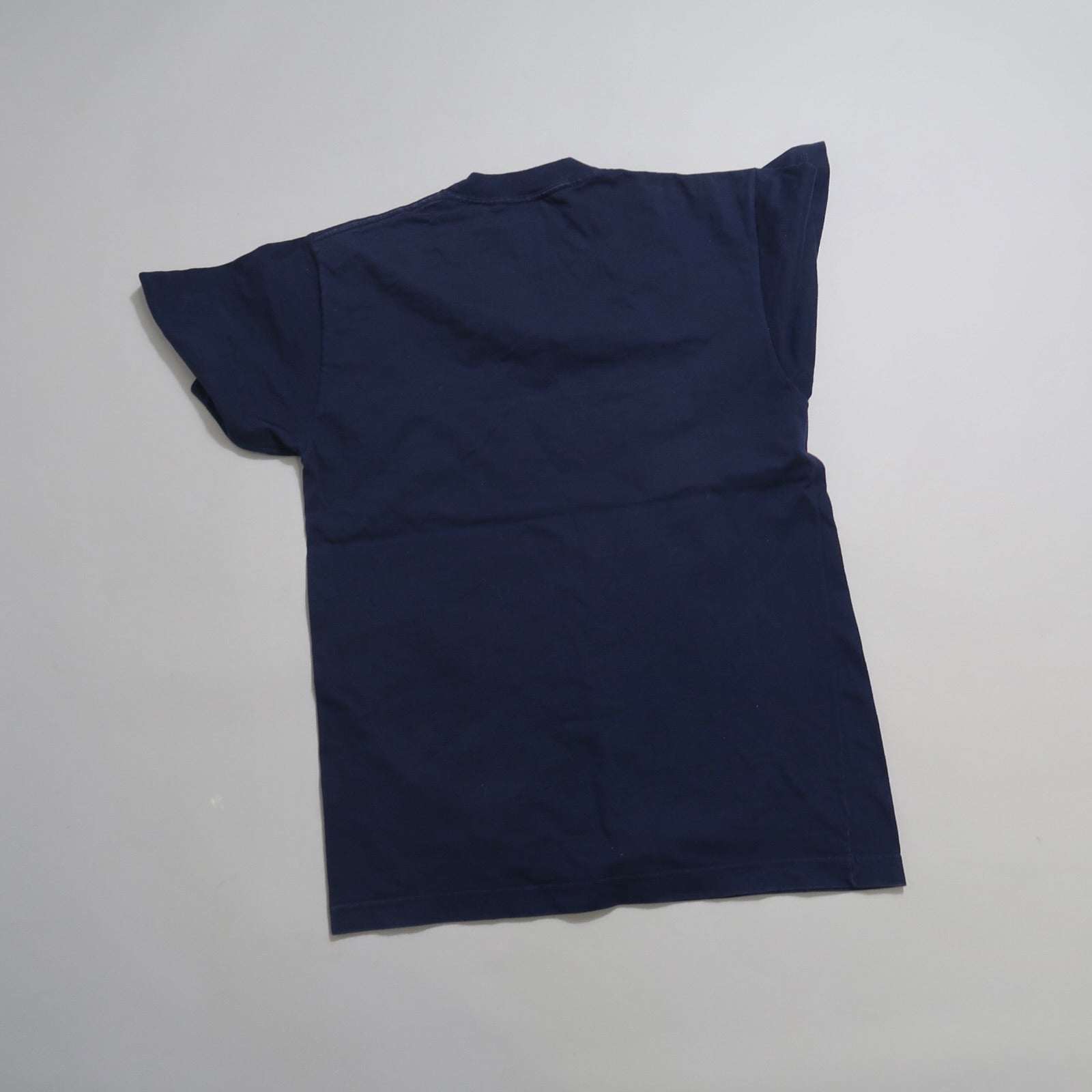Navy blue T-shirt laid flat on a light surface.