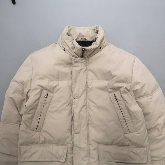 Beige puffer jacket with high collar and zippered pockets.