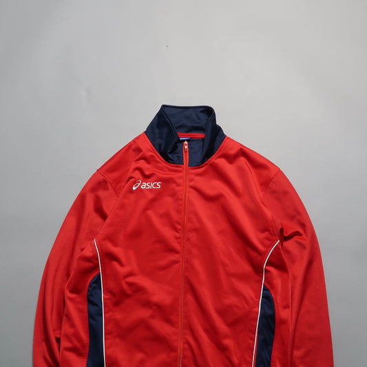 Red Asics sports jacket with navy accents on a gray background.