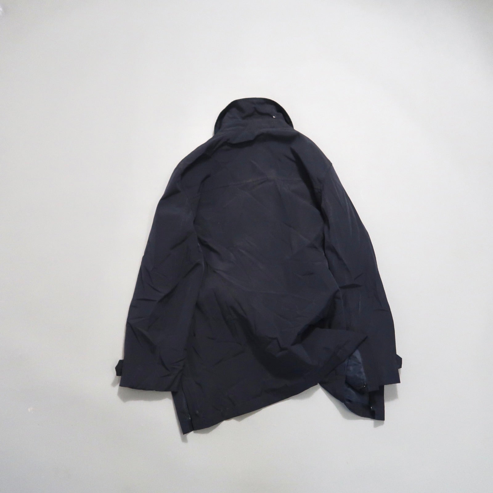Black jacket lying flat on a light surface.