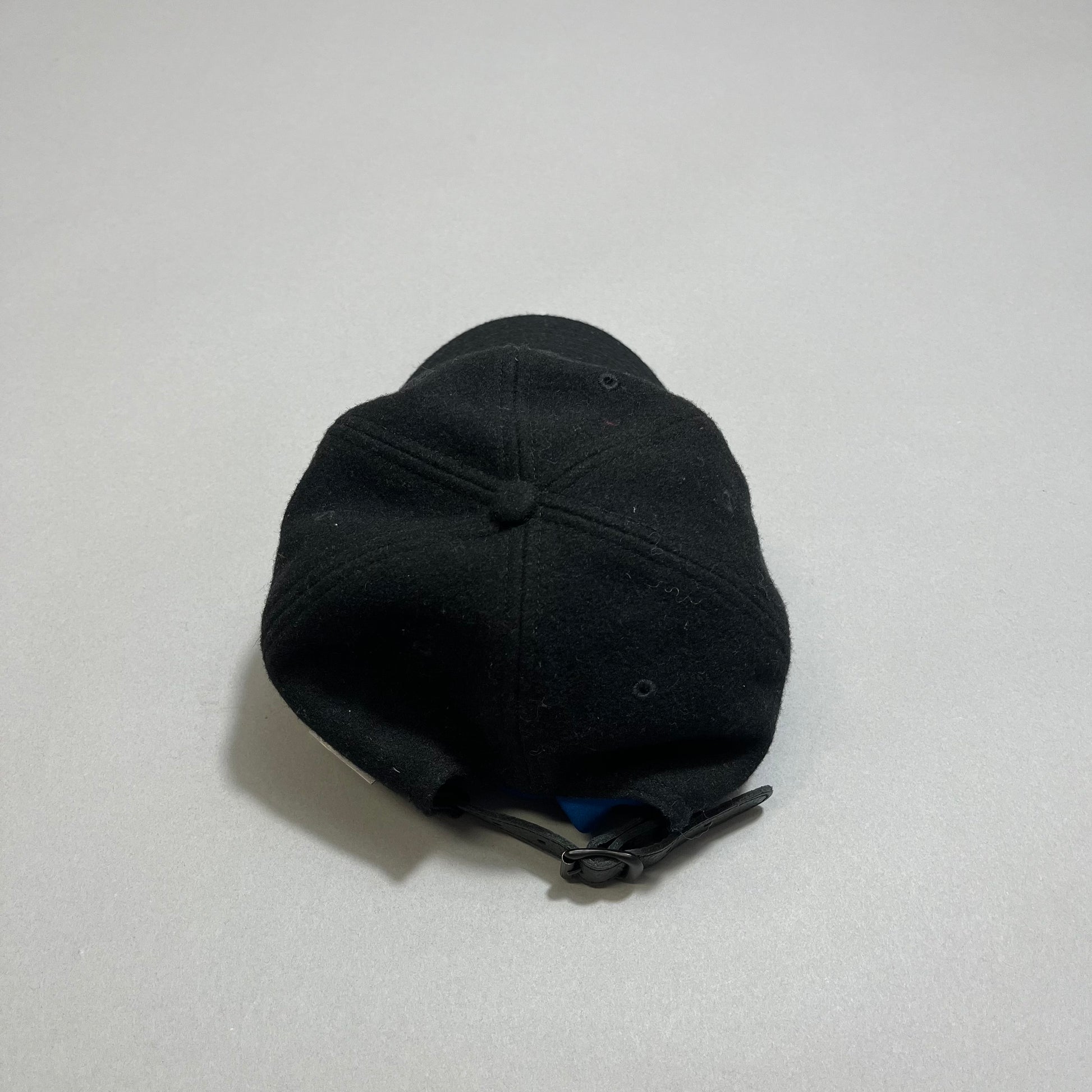 Black baseball cap with adjustable strap, placed upside down.