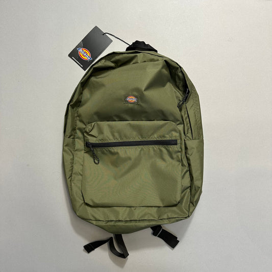 Green backpack with front pocket and tag attached on a light background.