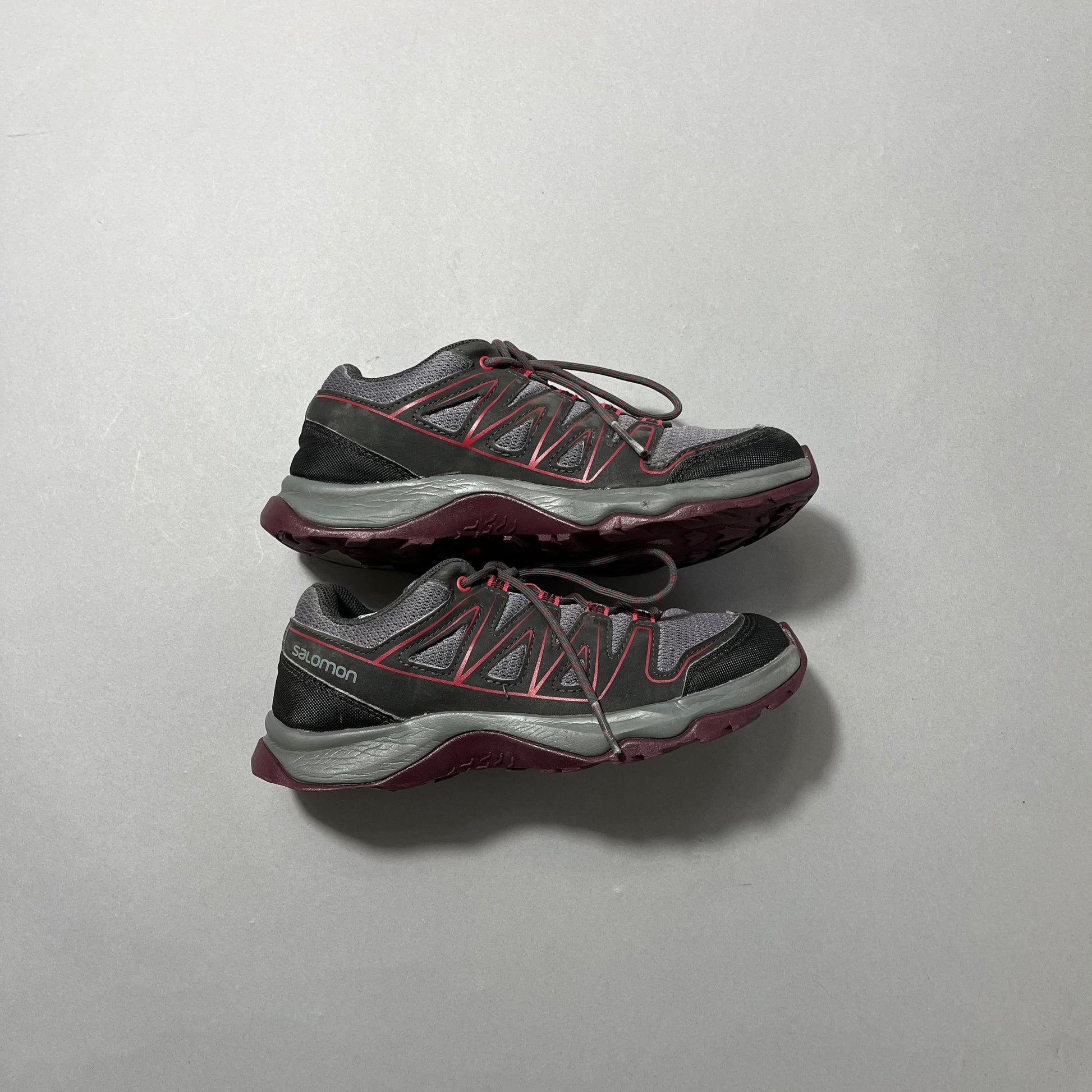 Trail running shoes with gray, red, and black design.