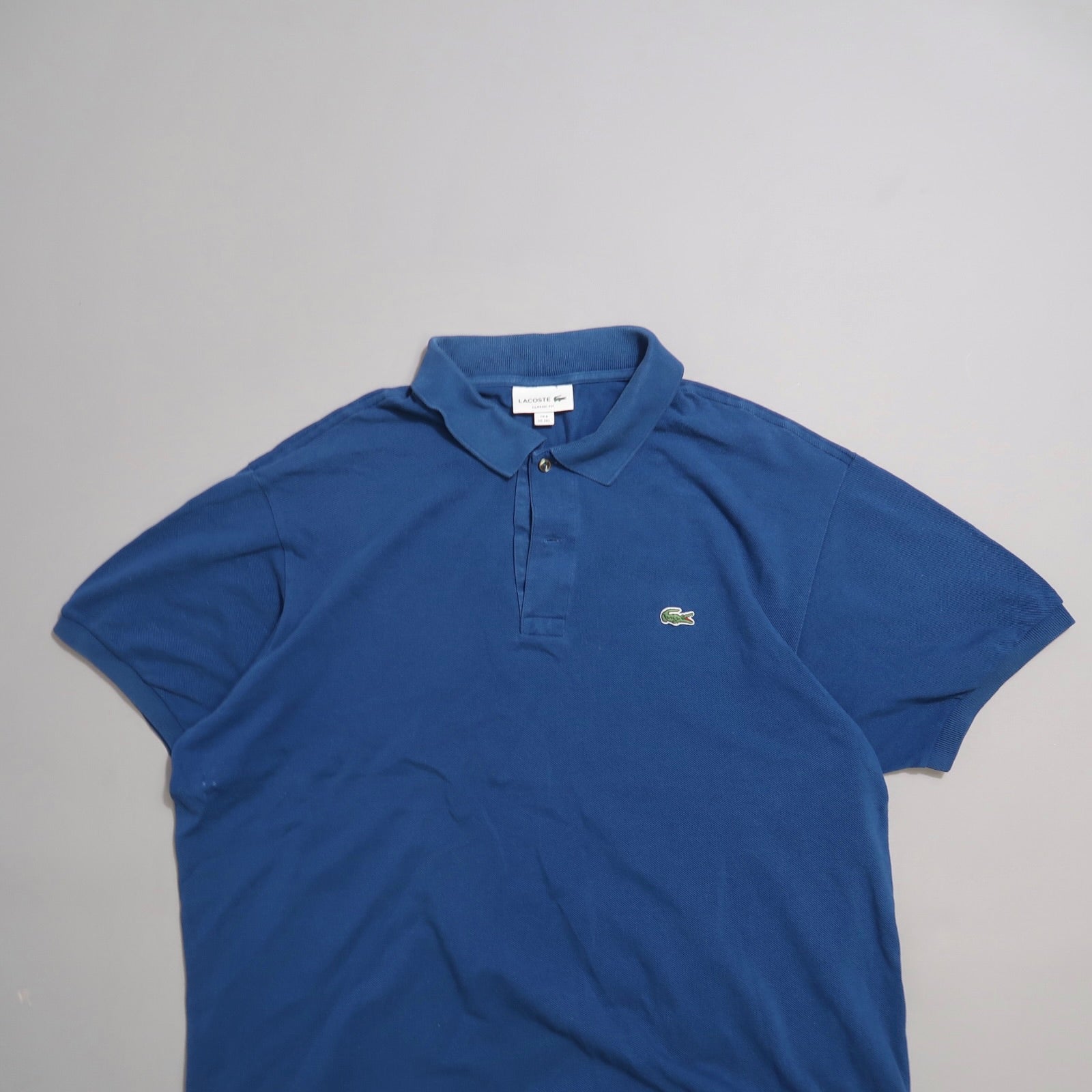 Blue polo shirt with a green logo on a plain background.