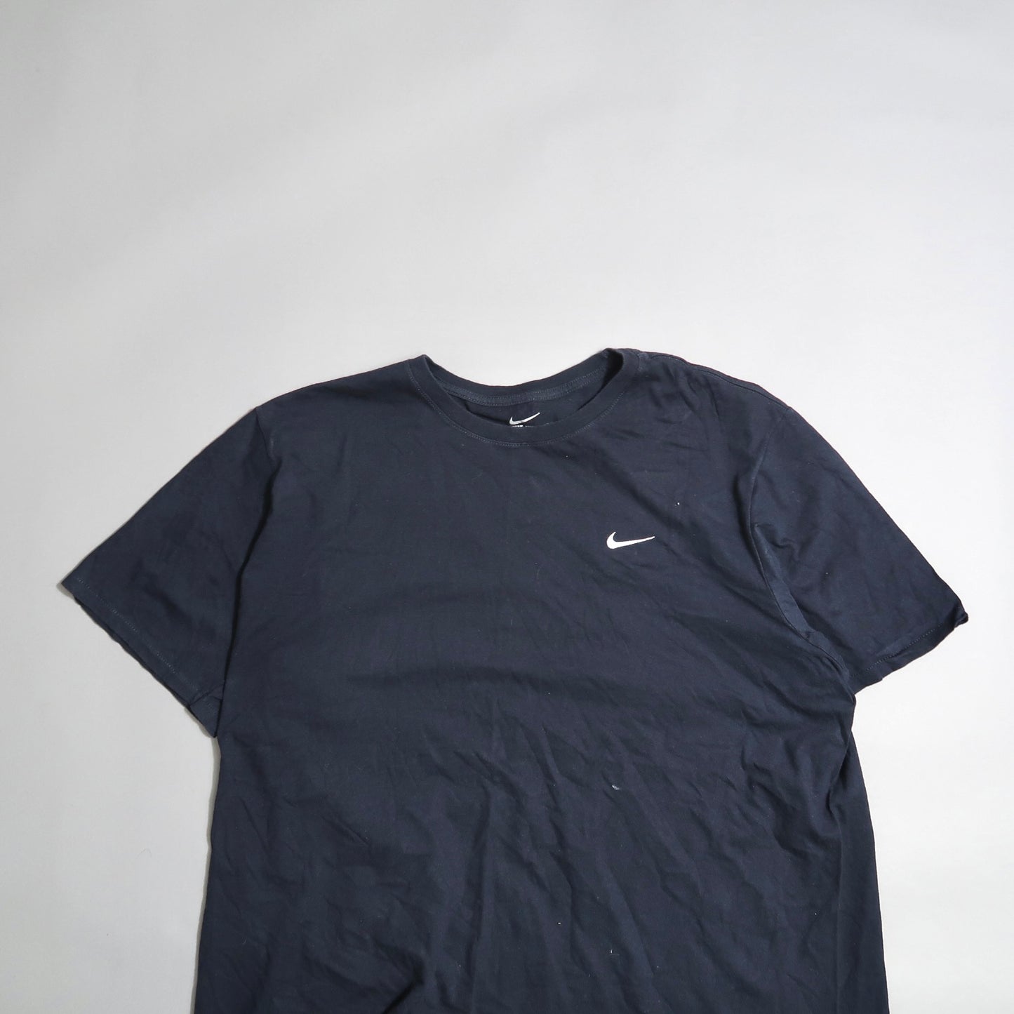 Dark Nike t-shirt with logo on the front, laid on a flat surface.