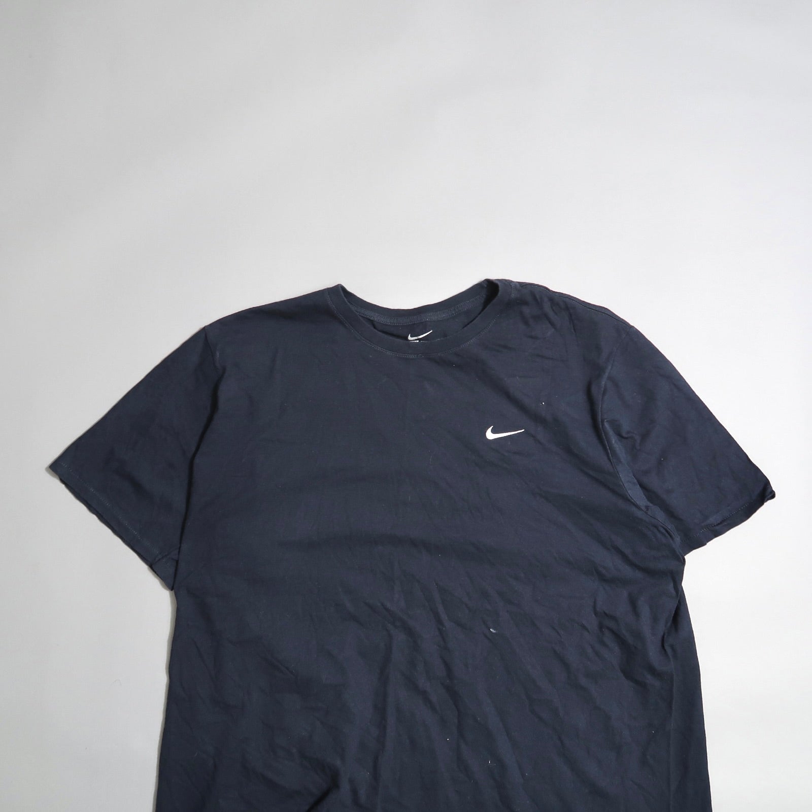 Dark Nike t-shirt with logo on the front, laid on a flat surface.